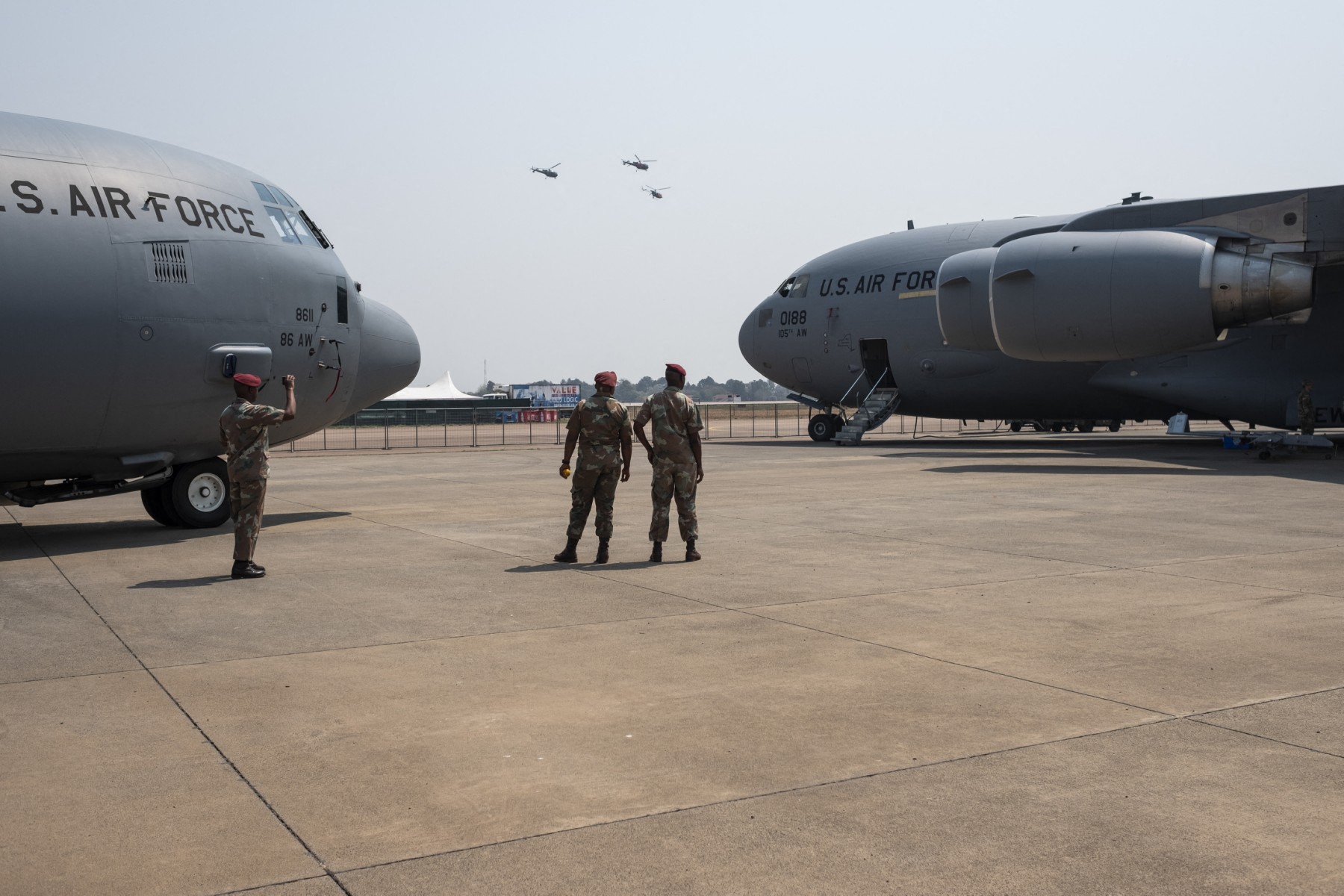 Members from the South African Defence Force stand between US Air Force's C130J Herculus (L) and C17 Globemaster III during the Africa Aerospace and Defence Expo on September 20, 2018