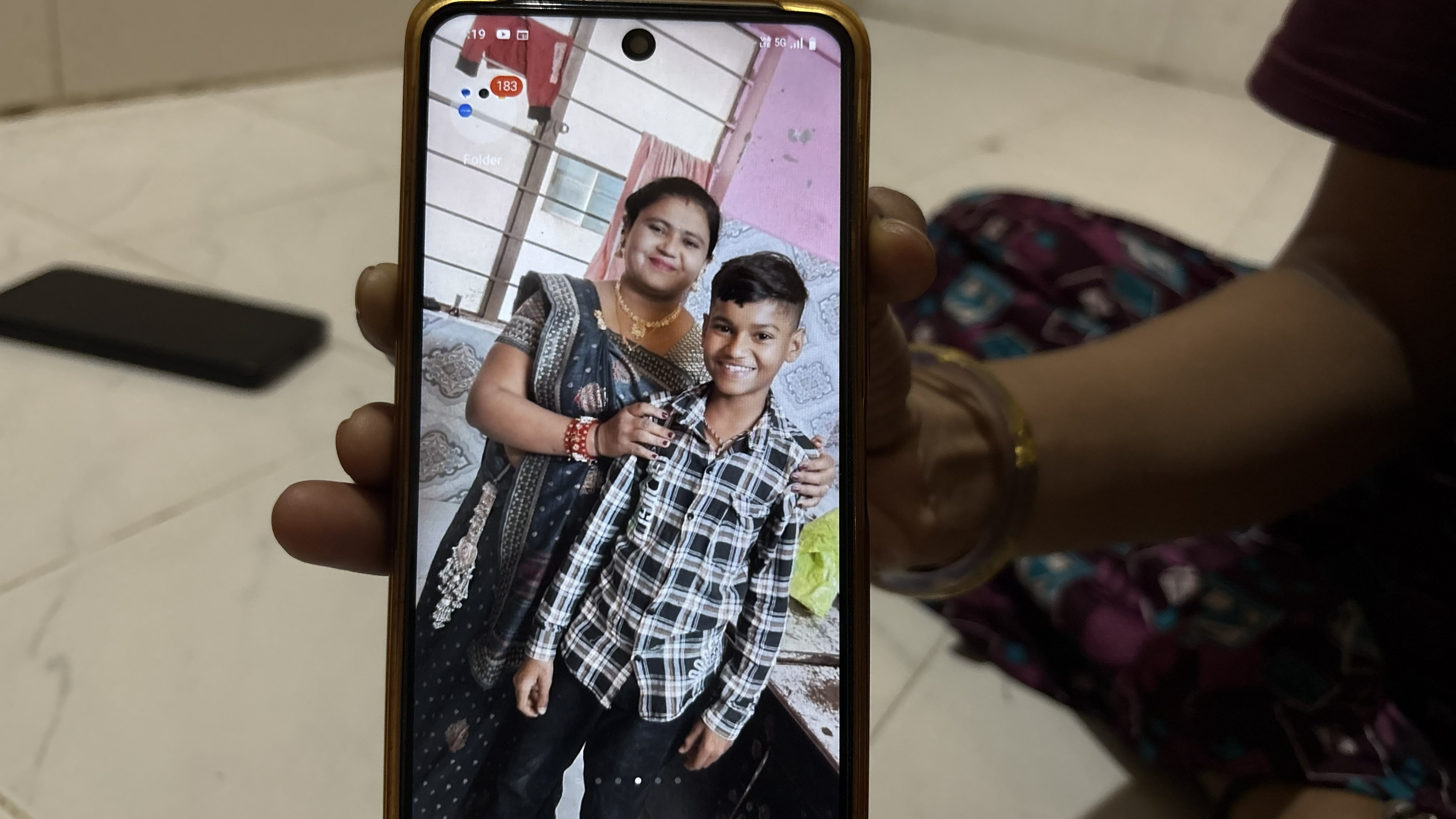 A photo Sita Patni and her son Aakash in happier times, seen on a mobile phone [Marhaba Hilali/ Al Jazeera]