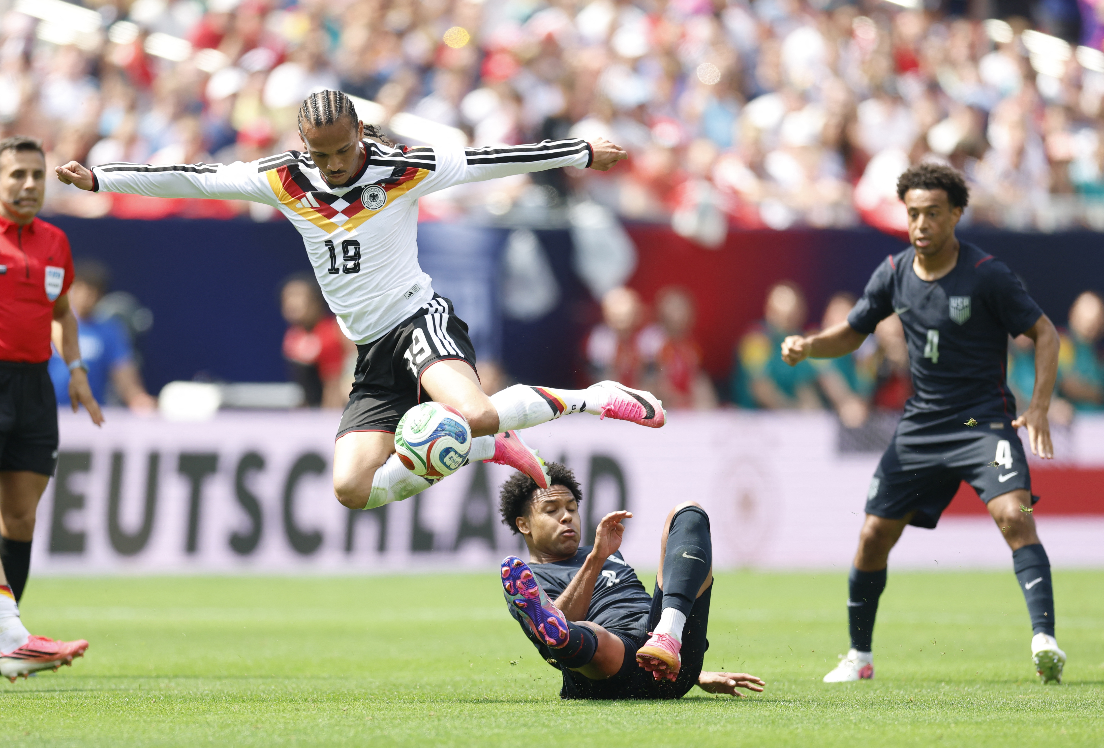 Germany's Leroy Sane jumps over Weston McKennie of the US during the international friendly football match between USA and Germany at Soldier Field in Chicago, Illinois on June 6, 2026. (Photo by KAMIL KRZACZYNSKI / AFP)
