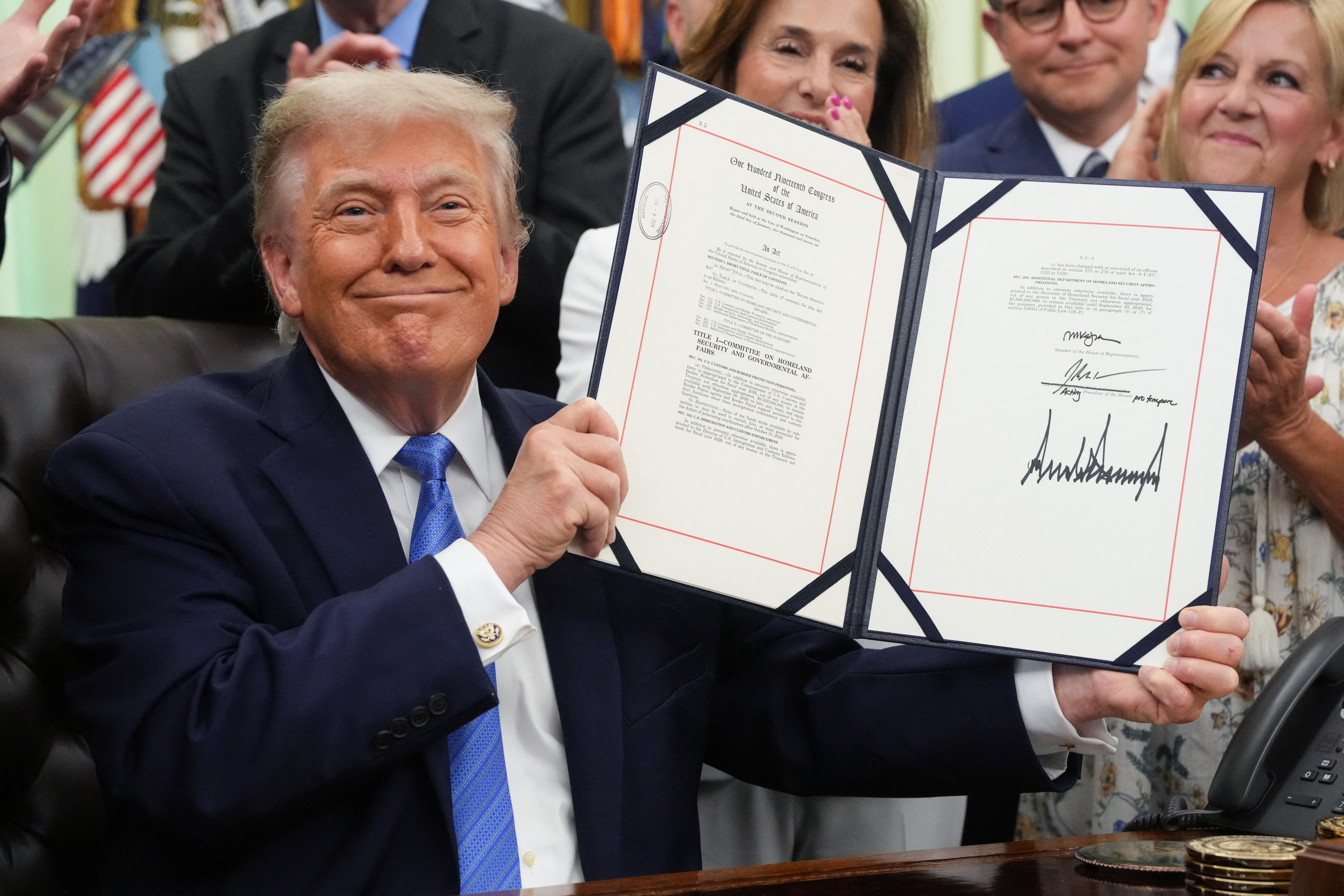 US President Donald Trump holds up the "Secure America Act" after signing it in the Oval Office of the White House in Washington, DC, on June 10, 2026.