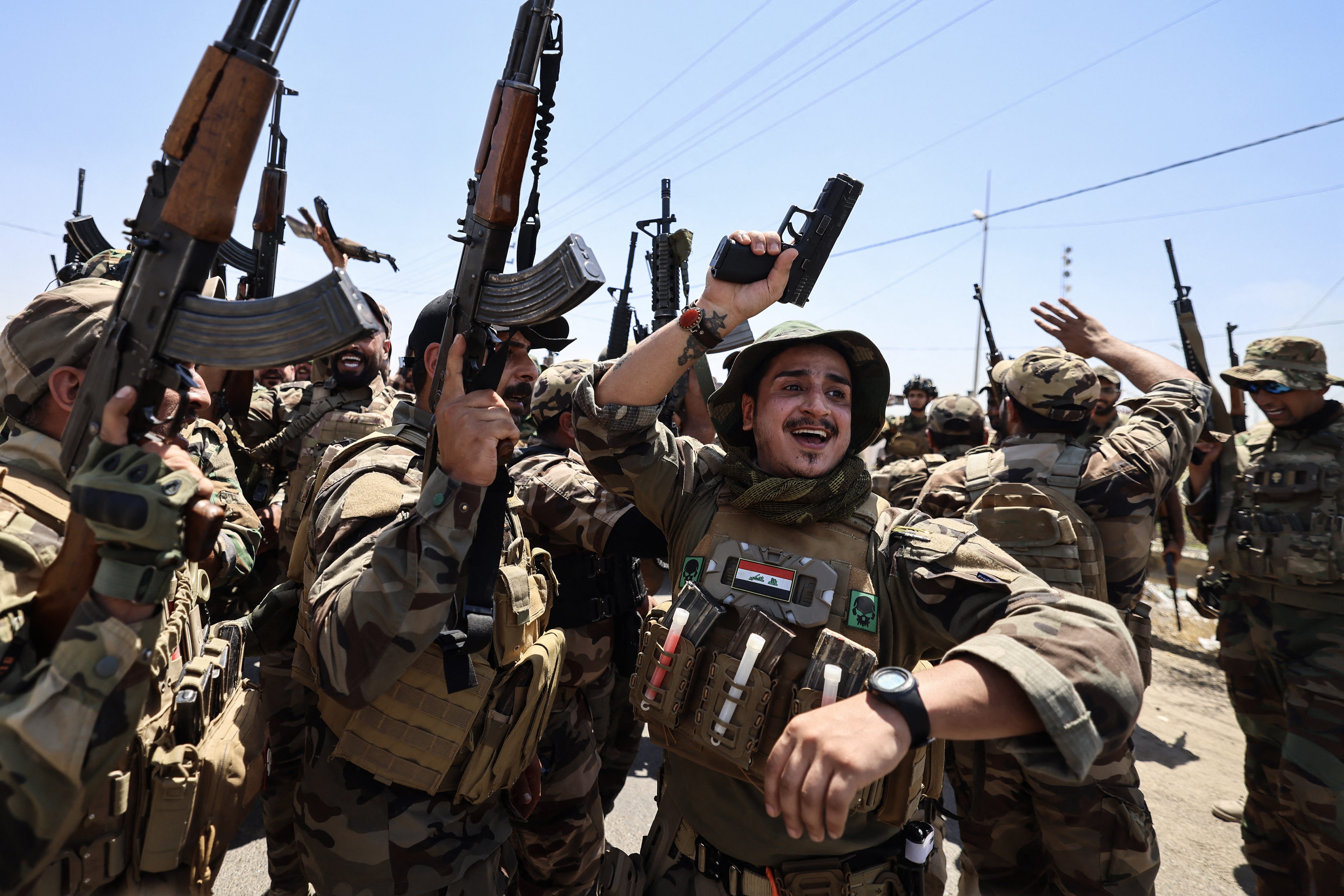 Armed, uniformed men celebrate and raise their guns in the air.