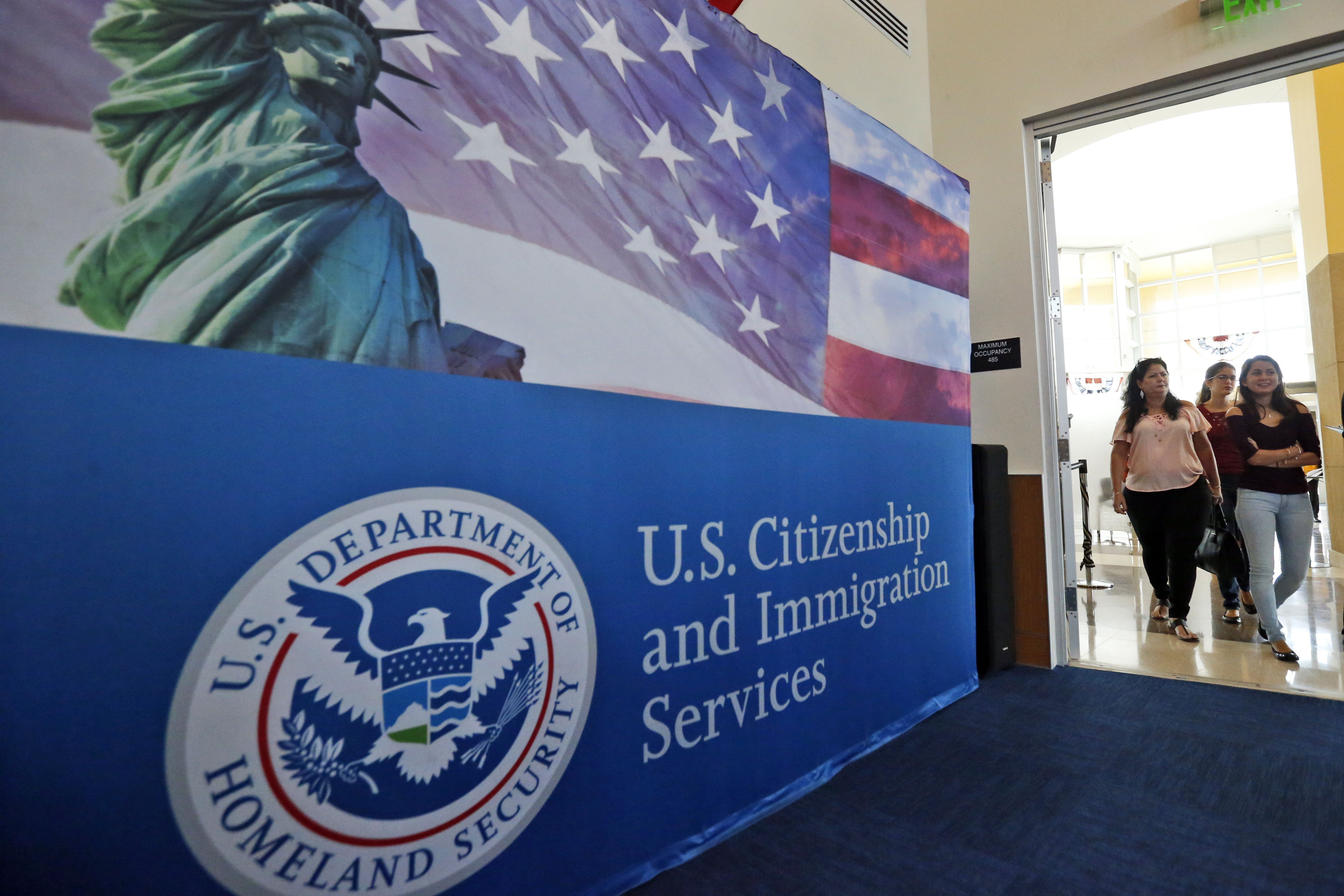 FILE - In this Aug. 17, 2018, file photo, people arrive before the start of a naturalization ceremony at the U.S. Citizenship and Immigration Services Miami Field Office in Miami. USCIS, The cash-strapped federal agency that oversees that nation's legal immigration system, scrapped plans Tuesday, Aug. 25, 2020, to furlough 13,000 employees, or nearly 70% of its workforce. The agency said it would maintain operations through September when the the fiscal year ends. (AP Photo/Wilfredo Lee, File)