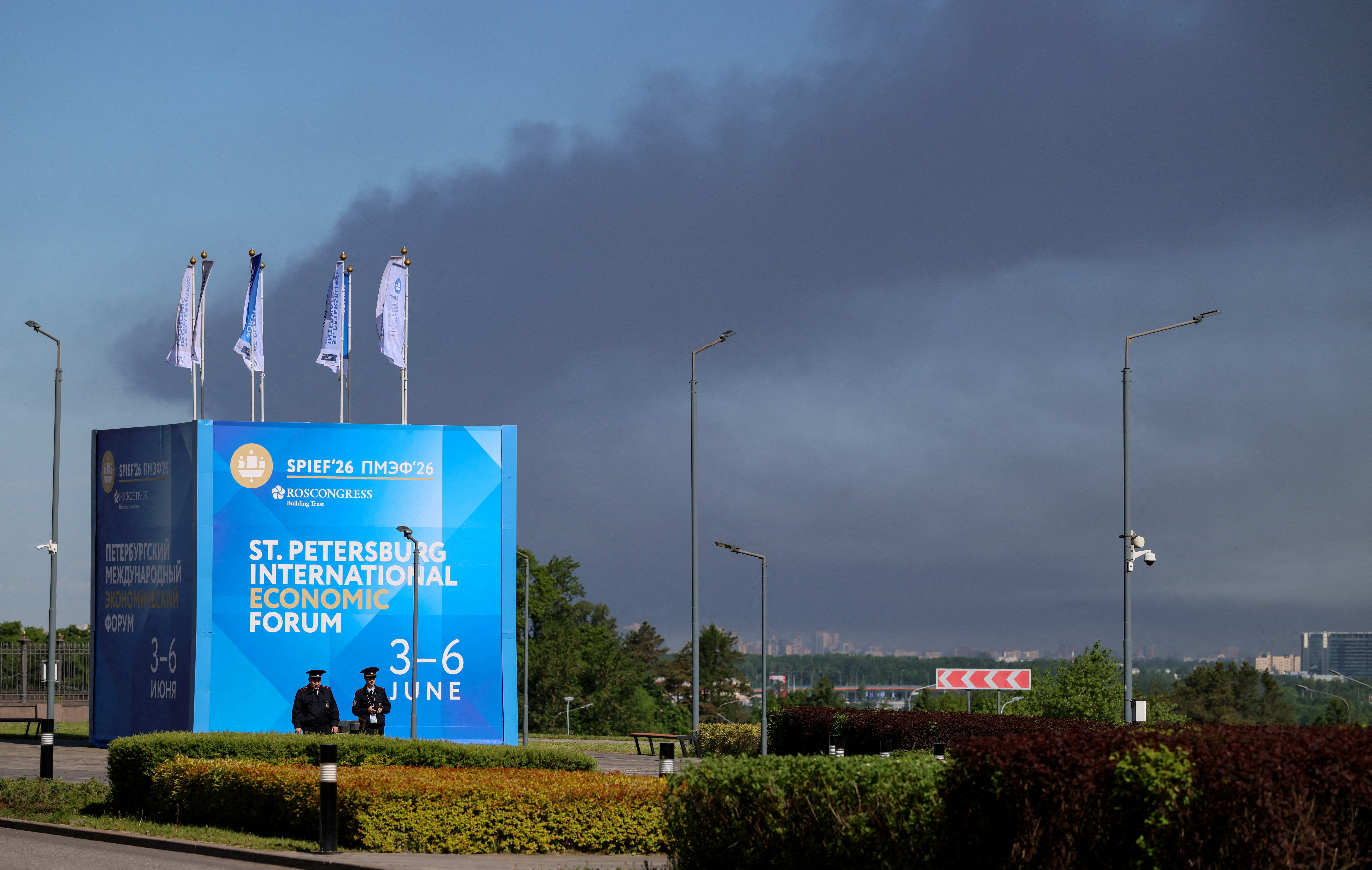 FILE PHOTO: Police officers stand in front of a banner and flags with the logo of the St. Petersburg International Economic Forum (SPIEF) as heavy smoke billows in the background after Ukrainian drones hit infrastructure, according to governor Alexander Beglov, in St Petersburg, Russia June 3, 2026. REUTERS/Stringer/File Photo