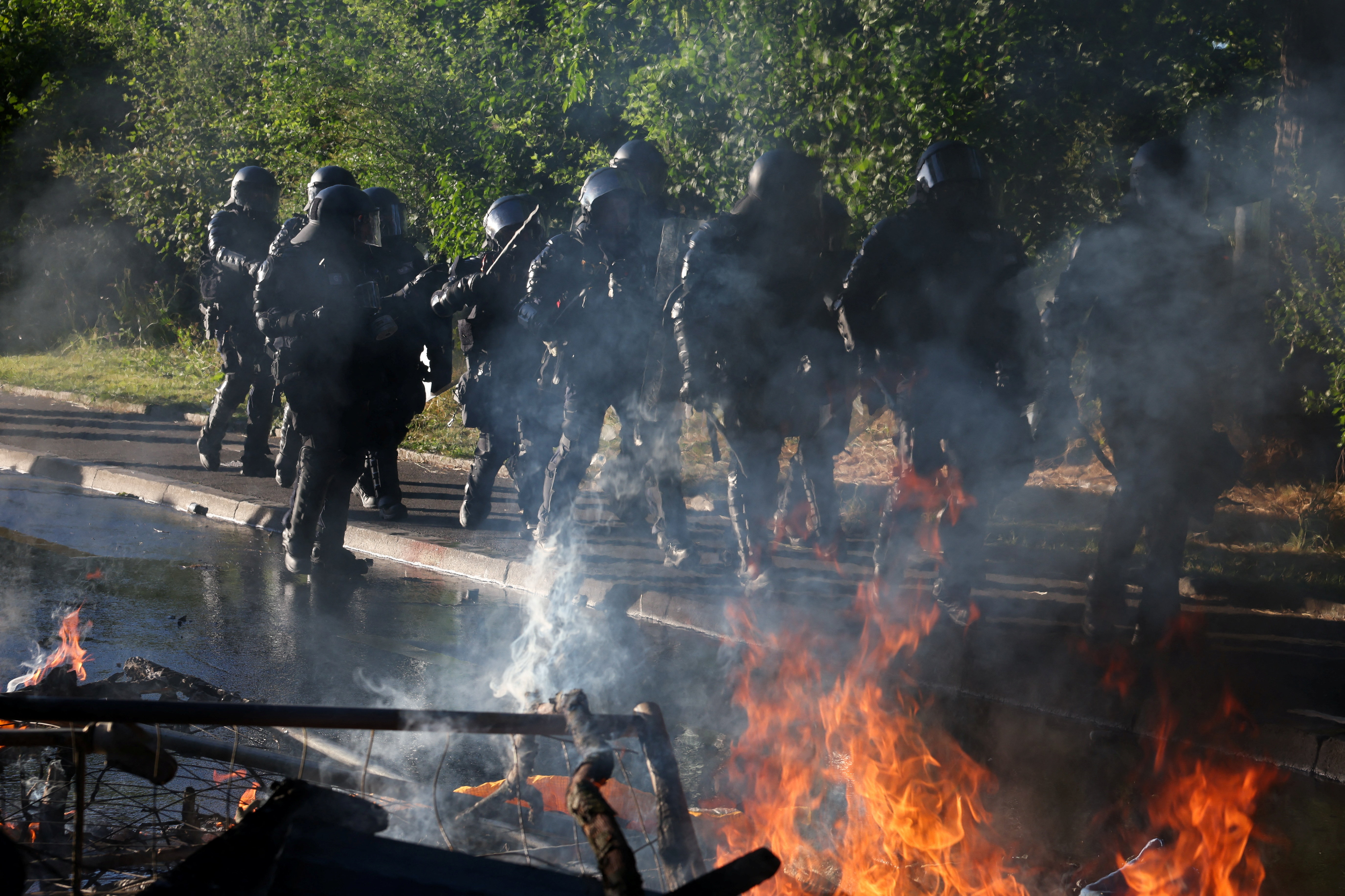 Riot police walk past fire during a protest against the upcoming G7 summit in Evian-les-Bains in France, in Geneva, Switzerland, June 14, 2026. REUTERS/Umit Bektas