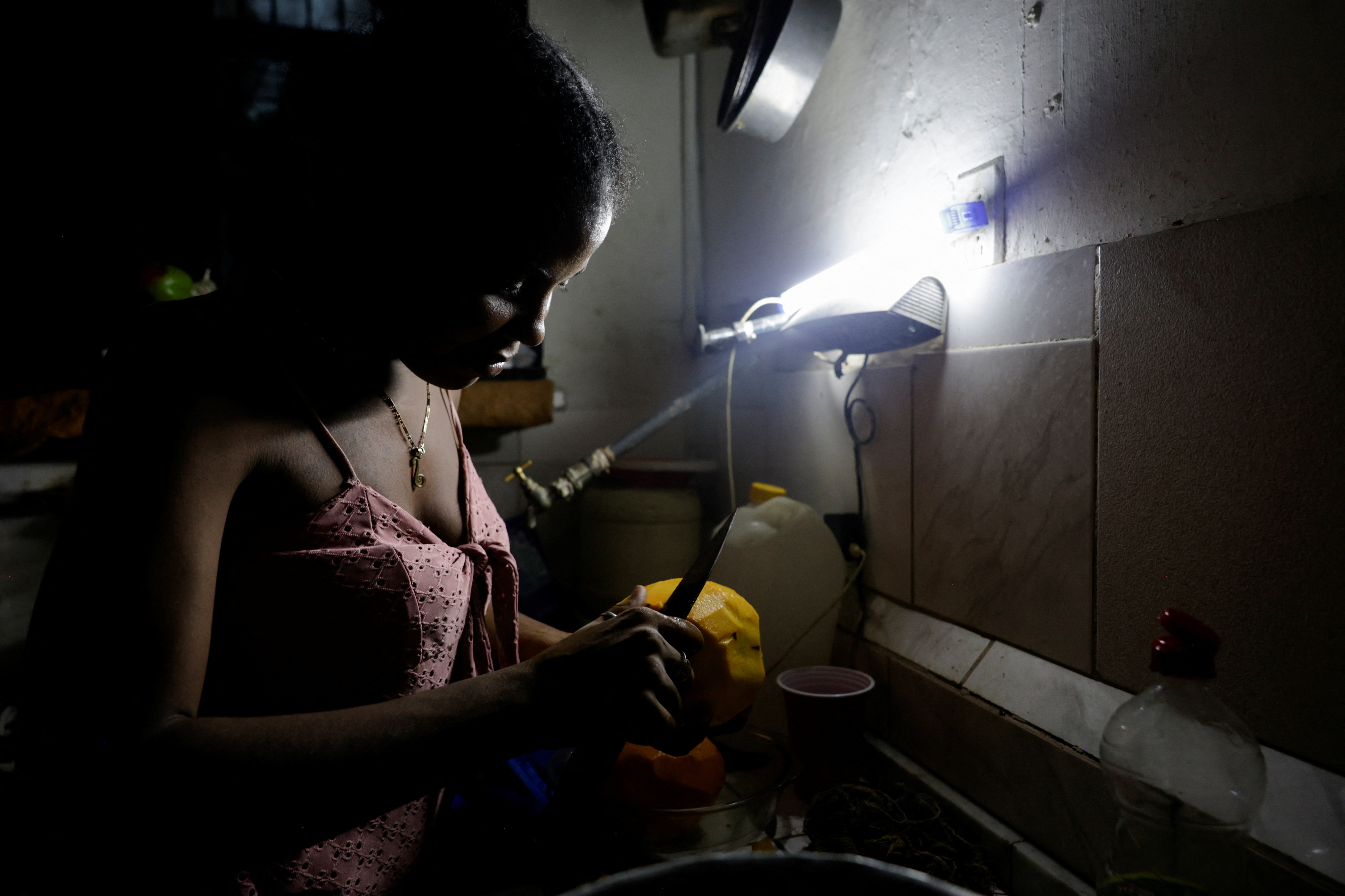 Maria Teresa Marti, 32, peels a mango for her children as Cuba's national power grid collapsed, marking the second total blackout in a week amid a severe energy crisis that has turned power outages into a daily reality, in Havana, Cuba, July 11, 2026. REUTERS/Norlys Perez