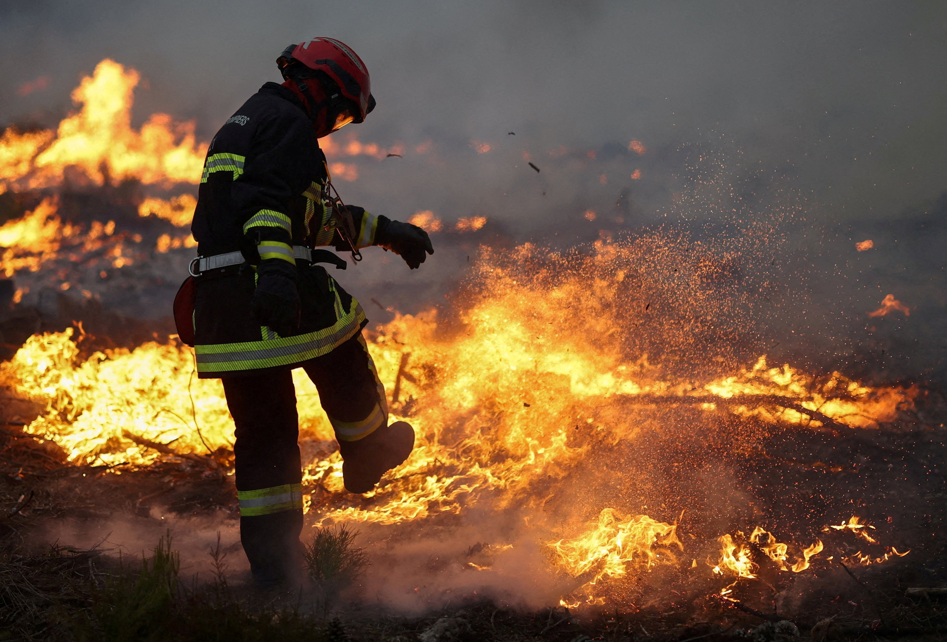 A firefighter works as flames burn during a wildfire at Ares, Gironde, on July 25, 2026 [Stephane Mahe/Reuters]
