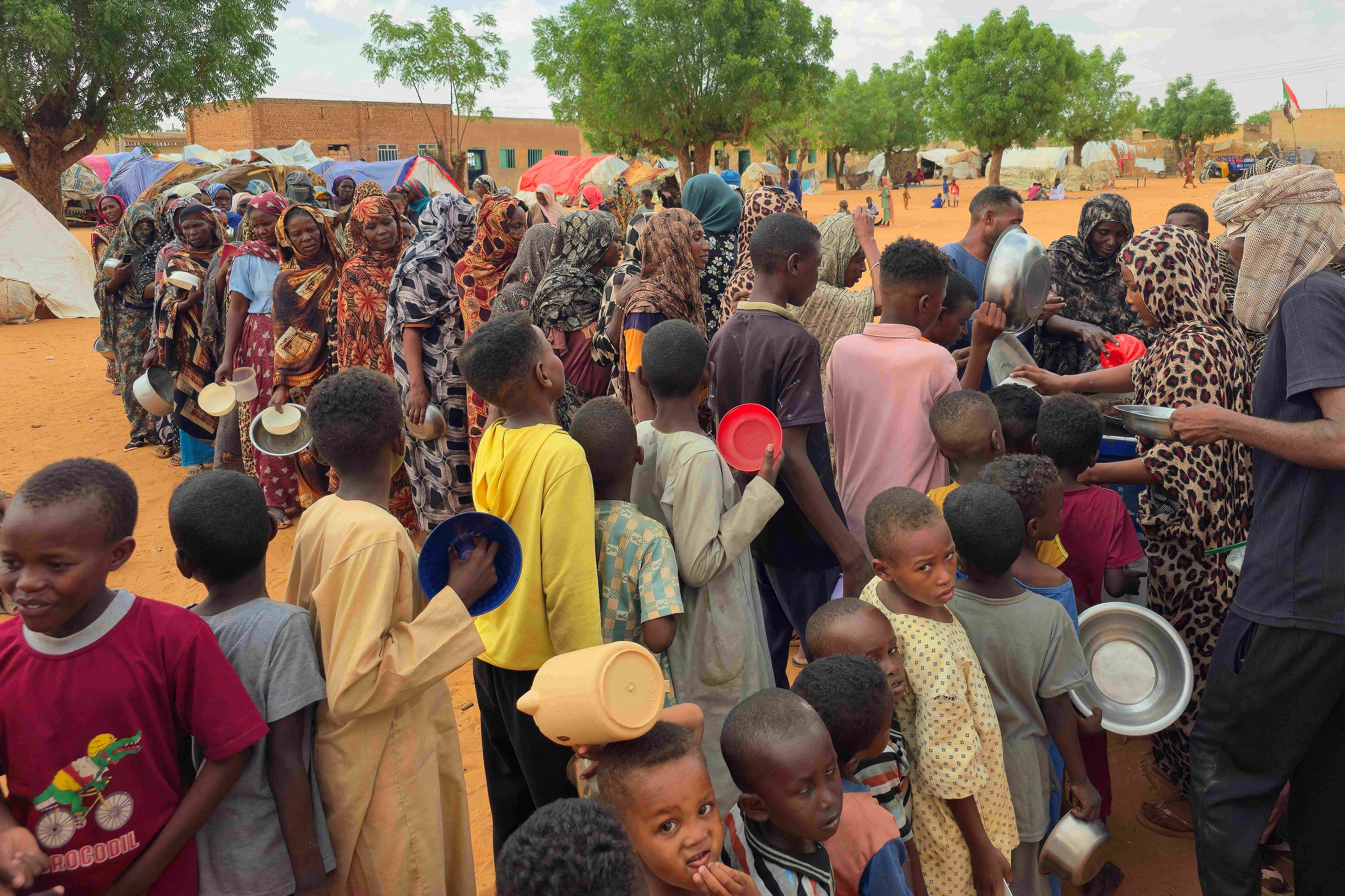 Women and children queue to receive food.
