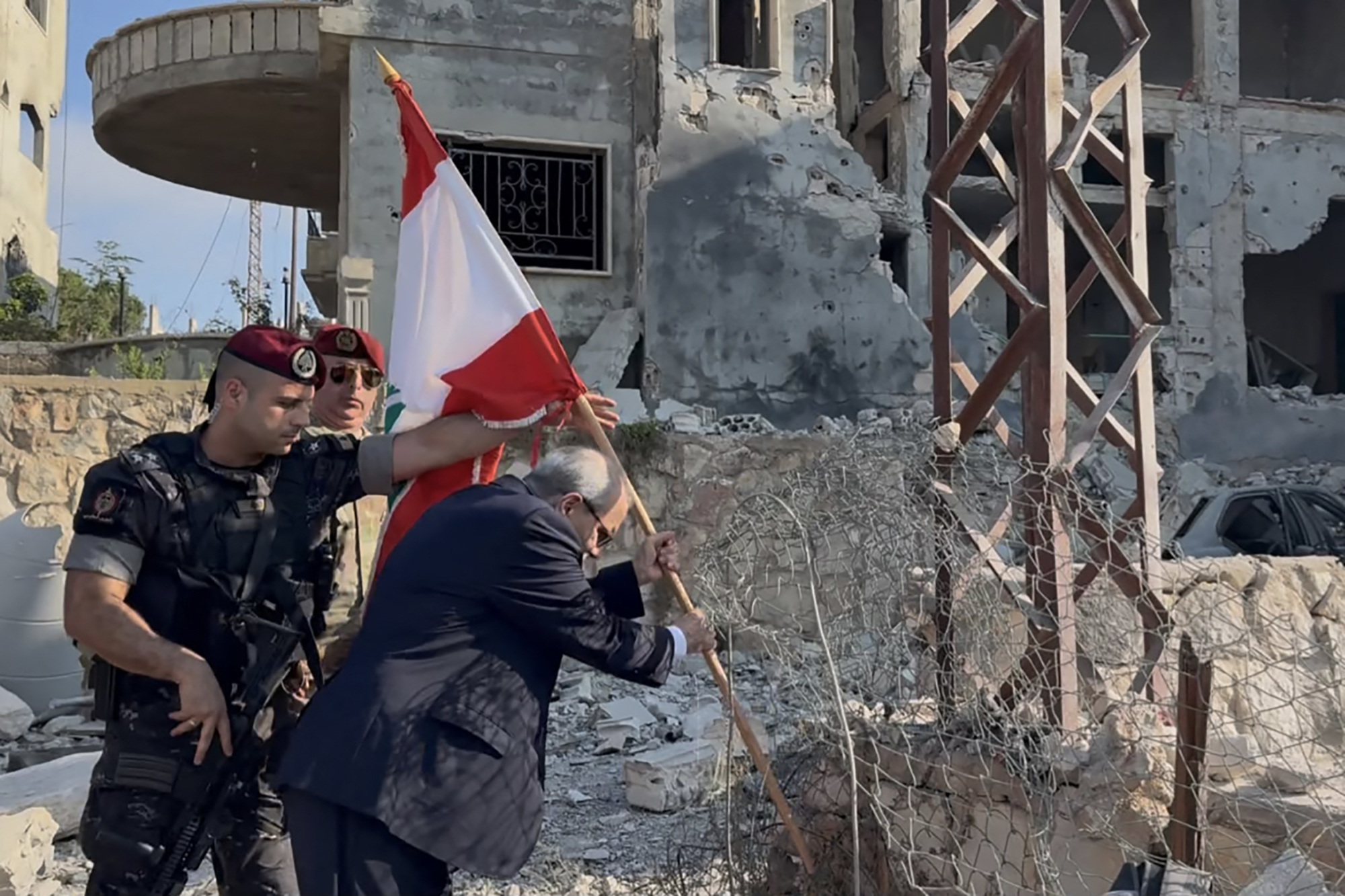 This handout picture released by the Lebanese prime minister's media office shows Lebanese Prime Minister Nawaf Salam placing a national flag along a damaged street in the southern village of Zawtar al-Gharbiya on July 22, 2026, after the withdrawal of Israeli troops from the area. Beirut is working towards a "complete Israeli withdrawal" from areas it occupies, Salam said on July 22 on a visit to the village where Lebanon's army recently deployed. (Photo by Lebanese Prime Minister's Press Office / AFP) / RESTRICTED TO EDITORIAL USE - MANDATORY CREDIT "AFP PHOTO / LEBANESE PRIME MINISTER'S PRESS OFFICE" - HANDOUT - NO MARKETING NO ADVERTISING CAMPAIGNS - DISTRIBUTED AS A SERVICE TO CLIENTS