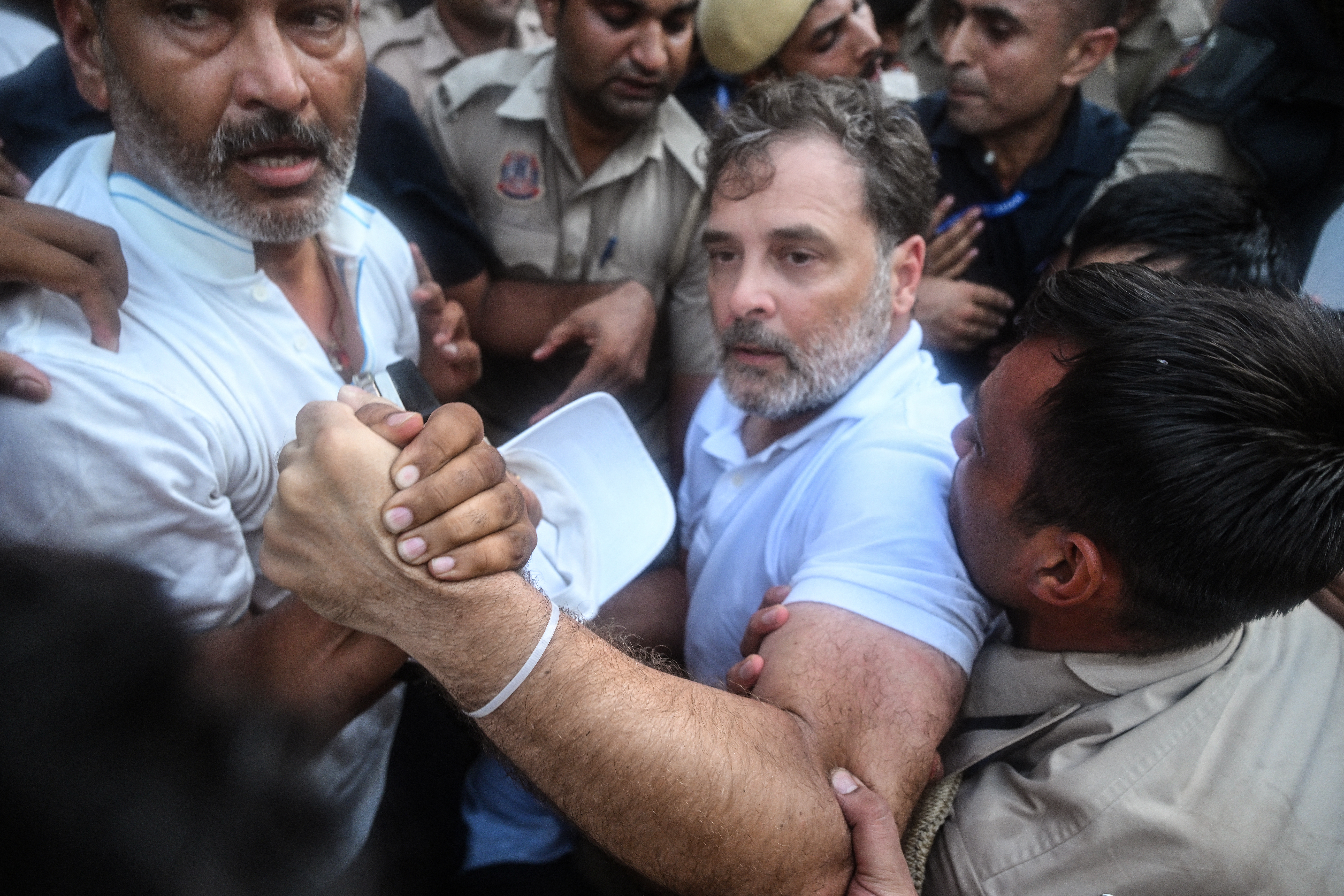 Security personnel detain India's Opposition Leader Rahul Gandhi (C) as he stages a sit-in protest calling for Prime Minister Narendra Modi's resignation outside the latter's residence in New Delhi on July 21, 2026, a day after police crackdown against the protesting Cockroach Janta Party (CJP) supporters demanding the Education Minister Dharmendra Pradhan step down over alleged NEET examination irregularities.