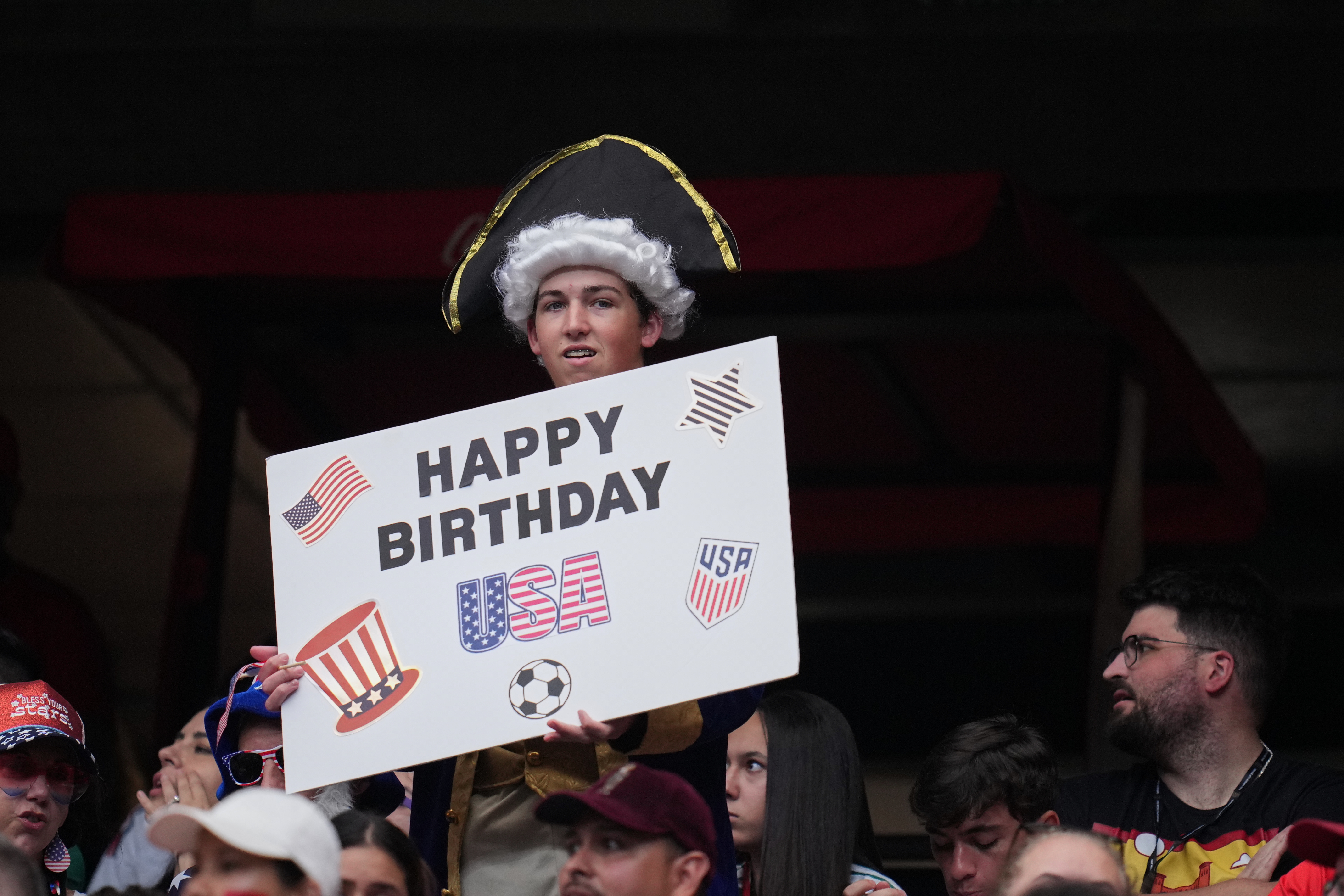 A fan wearing a U.S. costume and holding a placard celebrating America's 250th birthday waits before the World Cup round of 16 soccer match between Canada and Morocco, in Houston, Saturday, July 4, 2026. (AP Photo/Karen Warren)