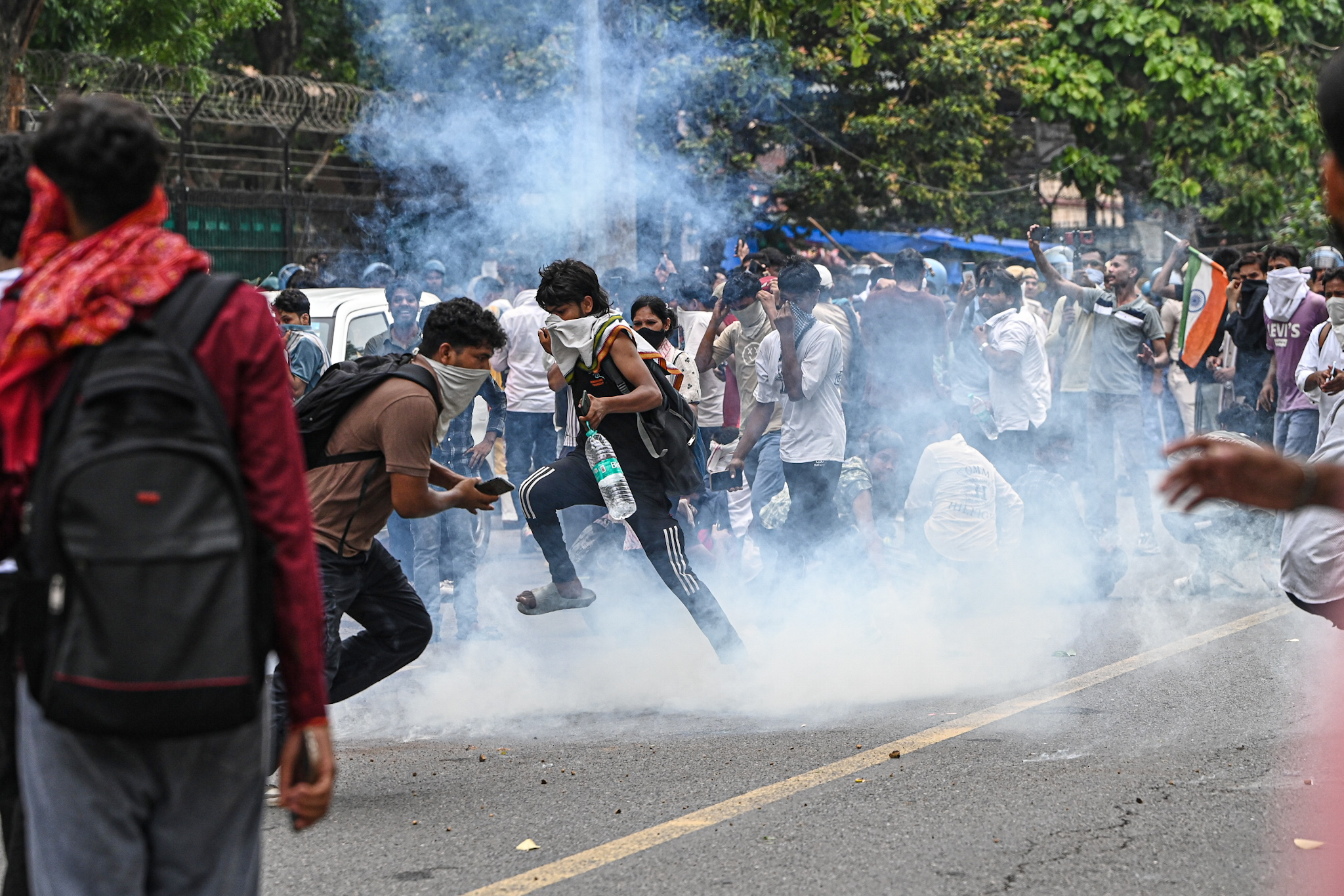 Cockroach Janta Party protesters try to neutralise a tear gas shell fired by police as they try to march towards India’s Parliament in New Delhi on July 20, 2026
