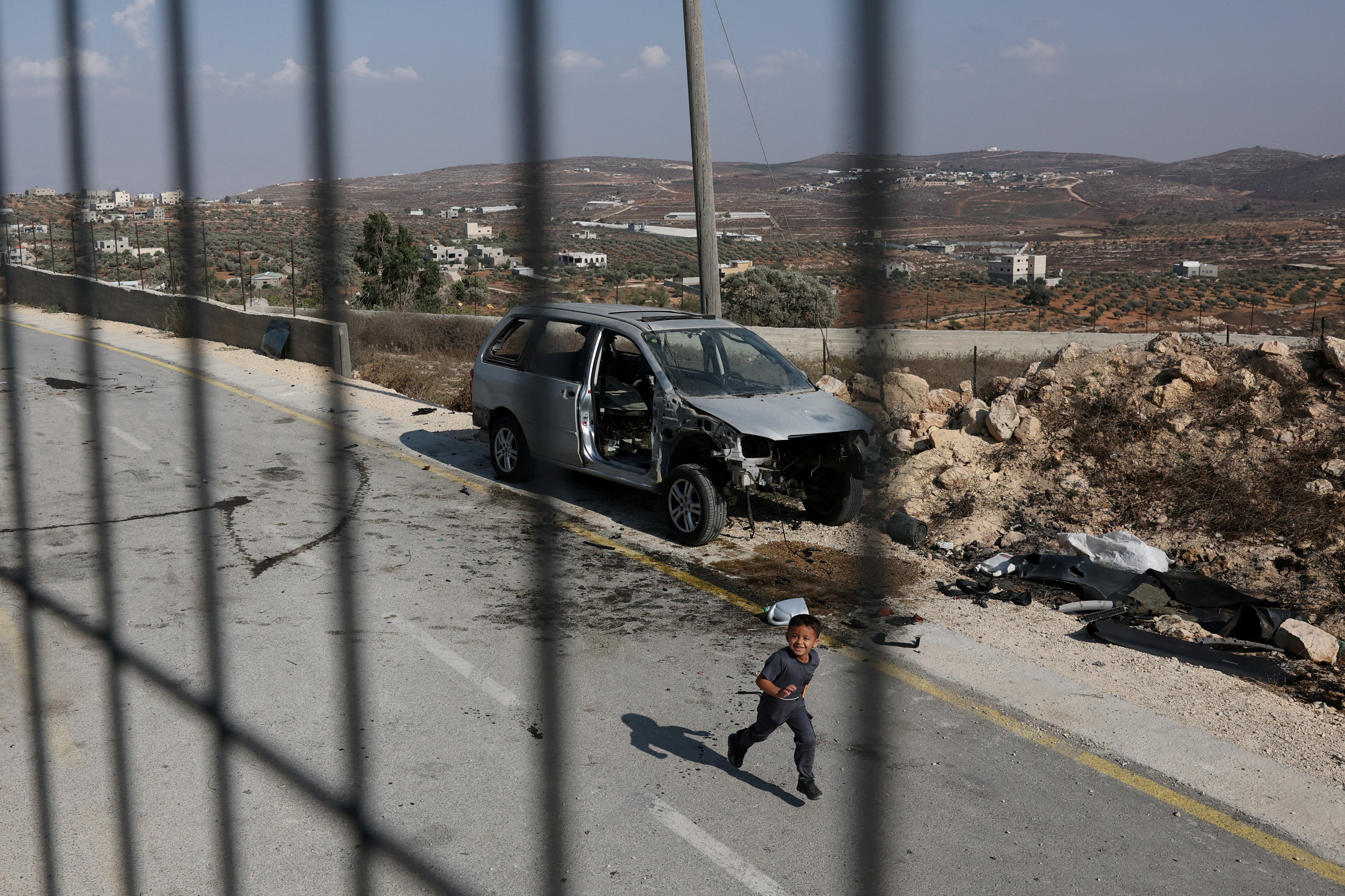 A Palestinian child plays on a road on the outskirts of Qusra, a Palestinian village in the Israeli-occupied West Bank [File: Ammar Awad/Reuters]