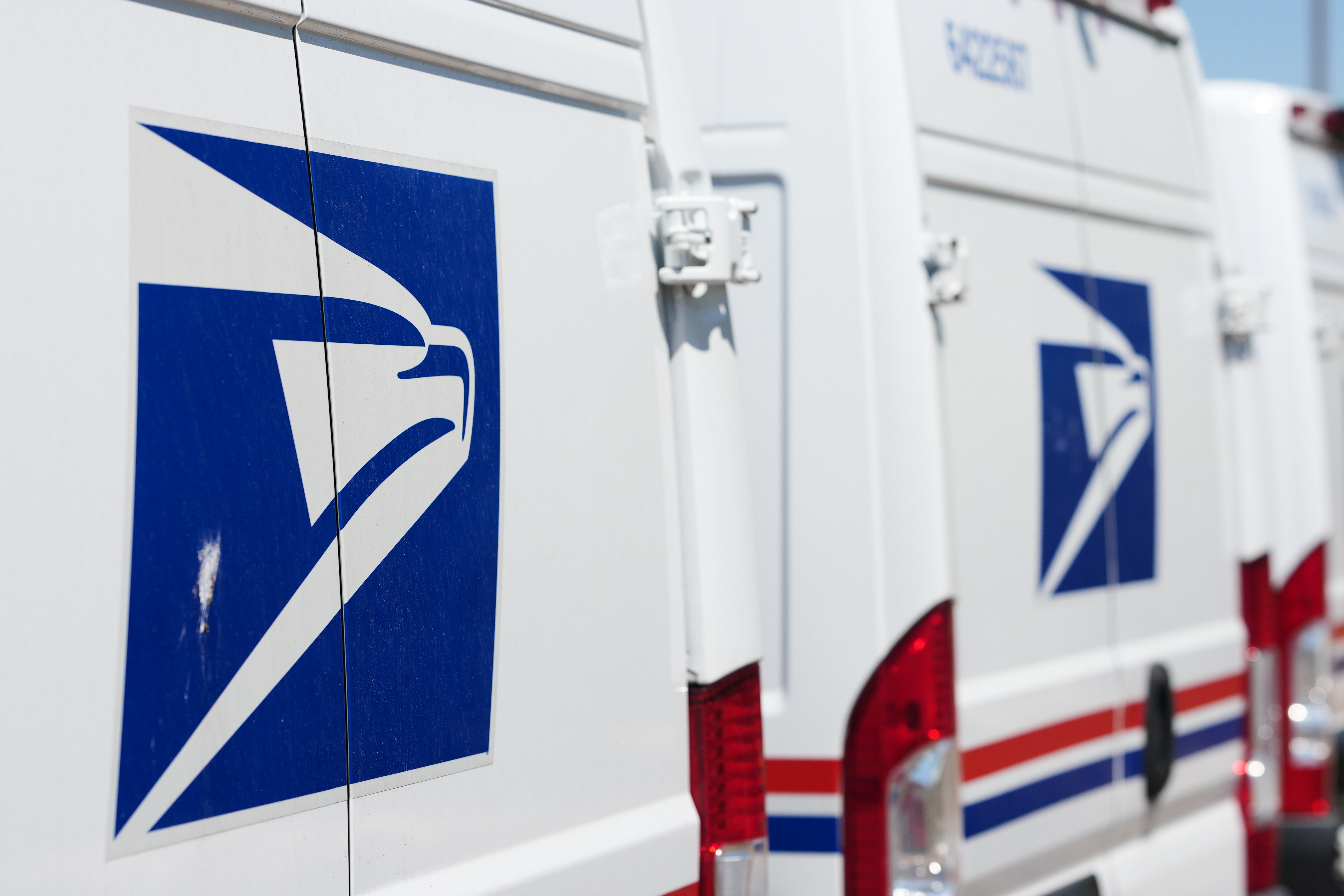 Delivery vans bearing the logo of US Postal Service