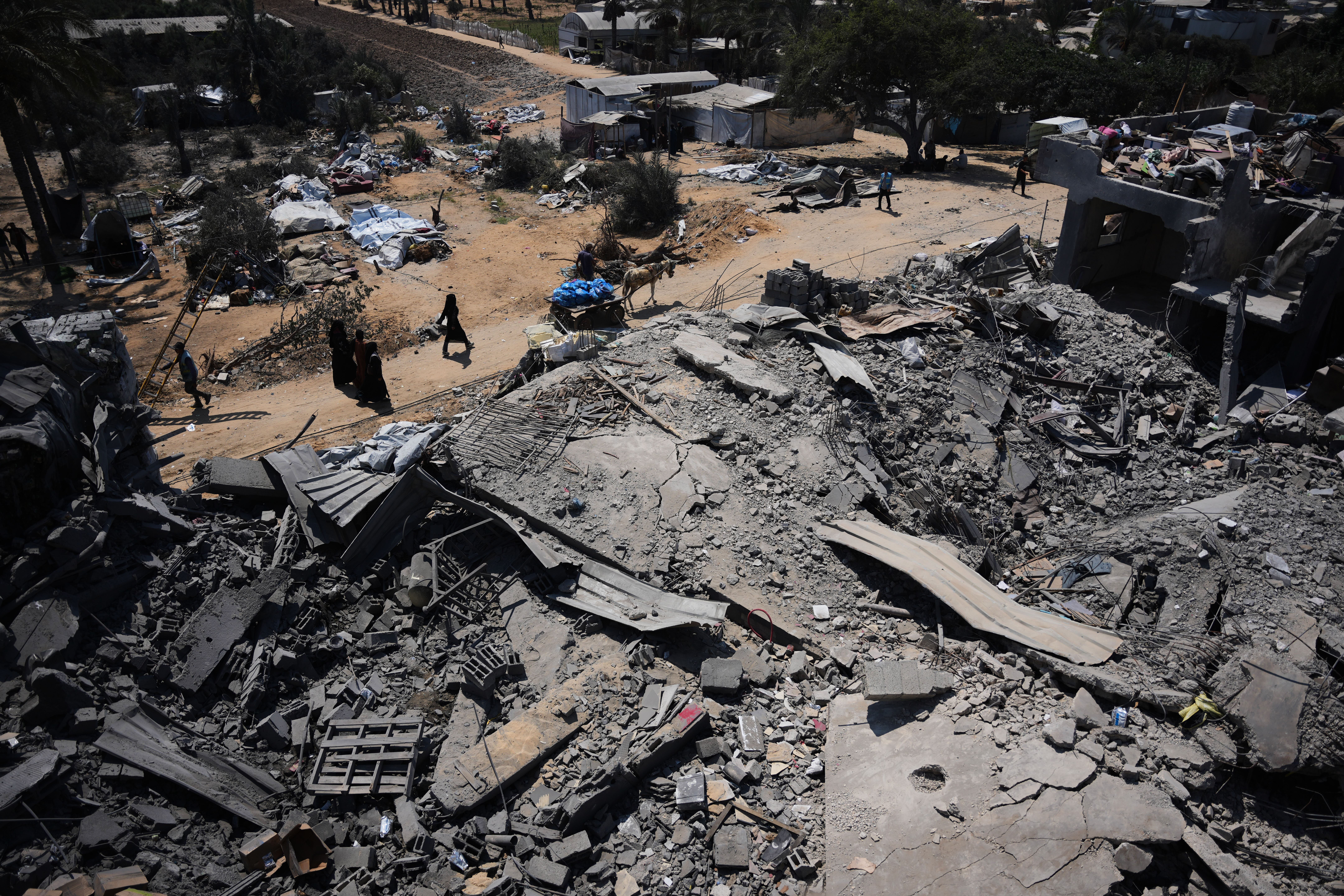 Palestinians walk past a food-aid warehouse damaged in an Israeli air strike that targeted a nearby house in Deir al-Balah, central Gaza on August 26, 2026.
