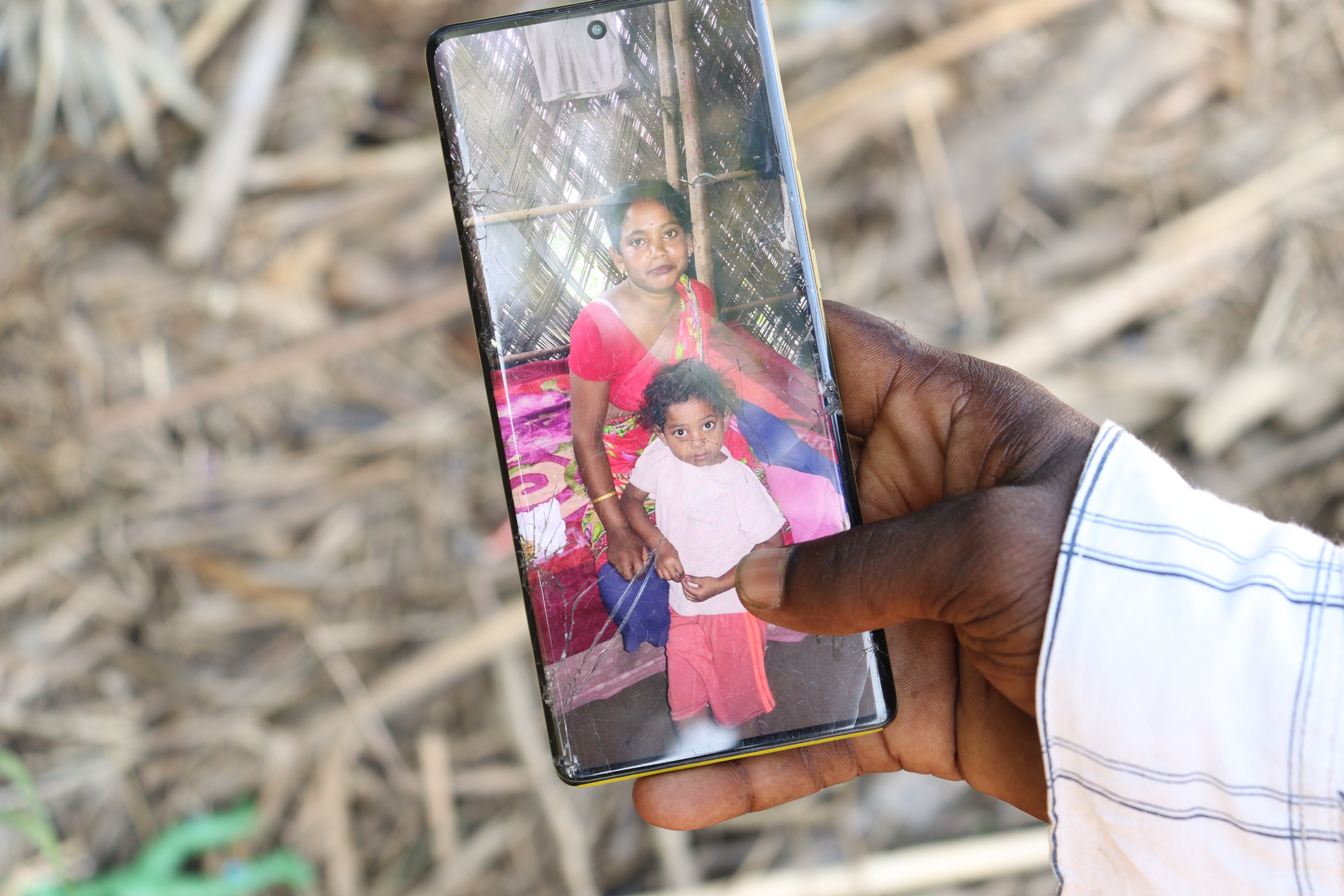 Man holds a phone with a photo of his wife and daughter.