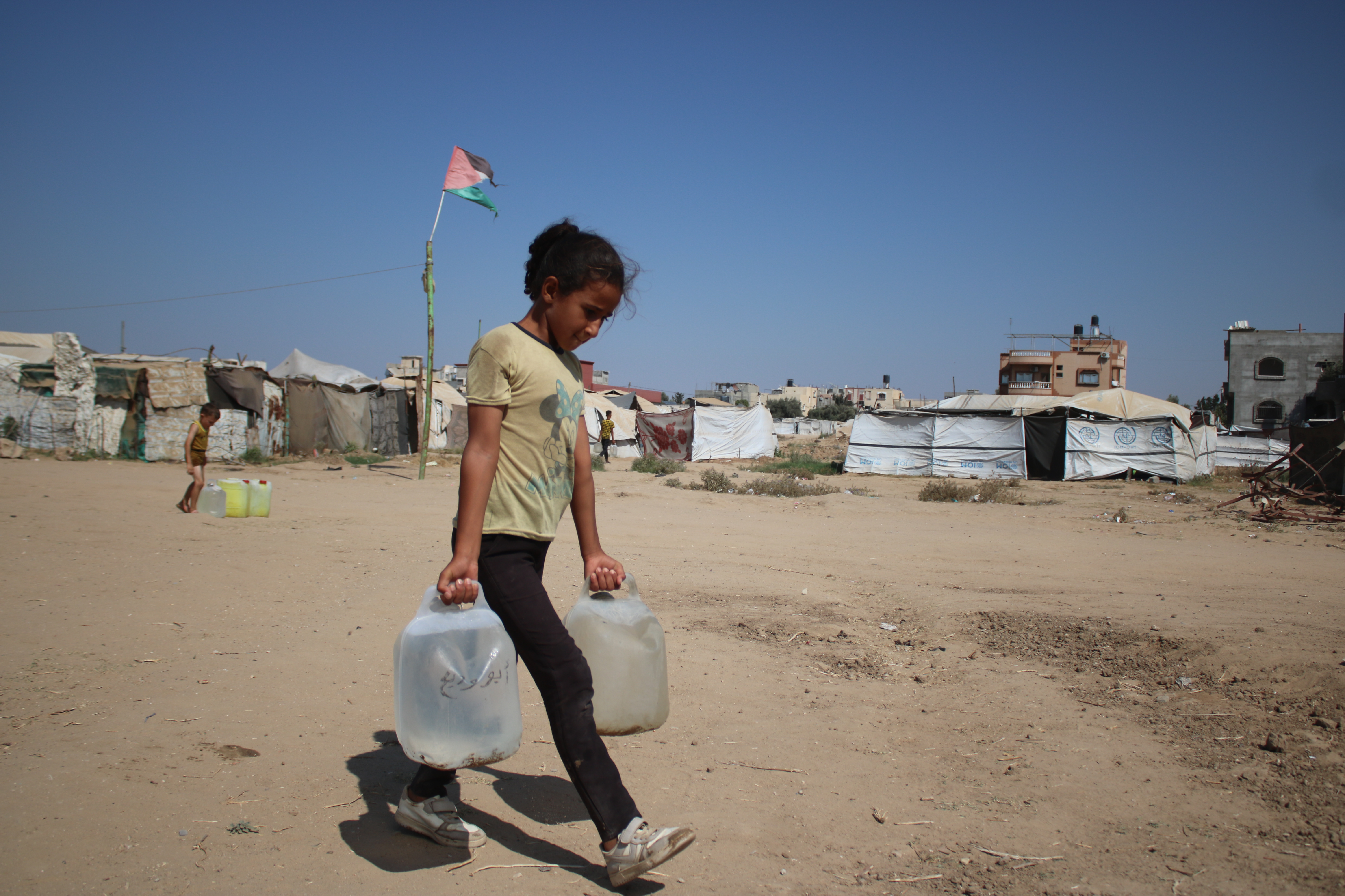 Maysara carrying water back to her family’s tent