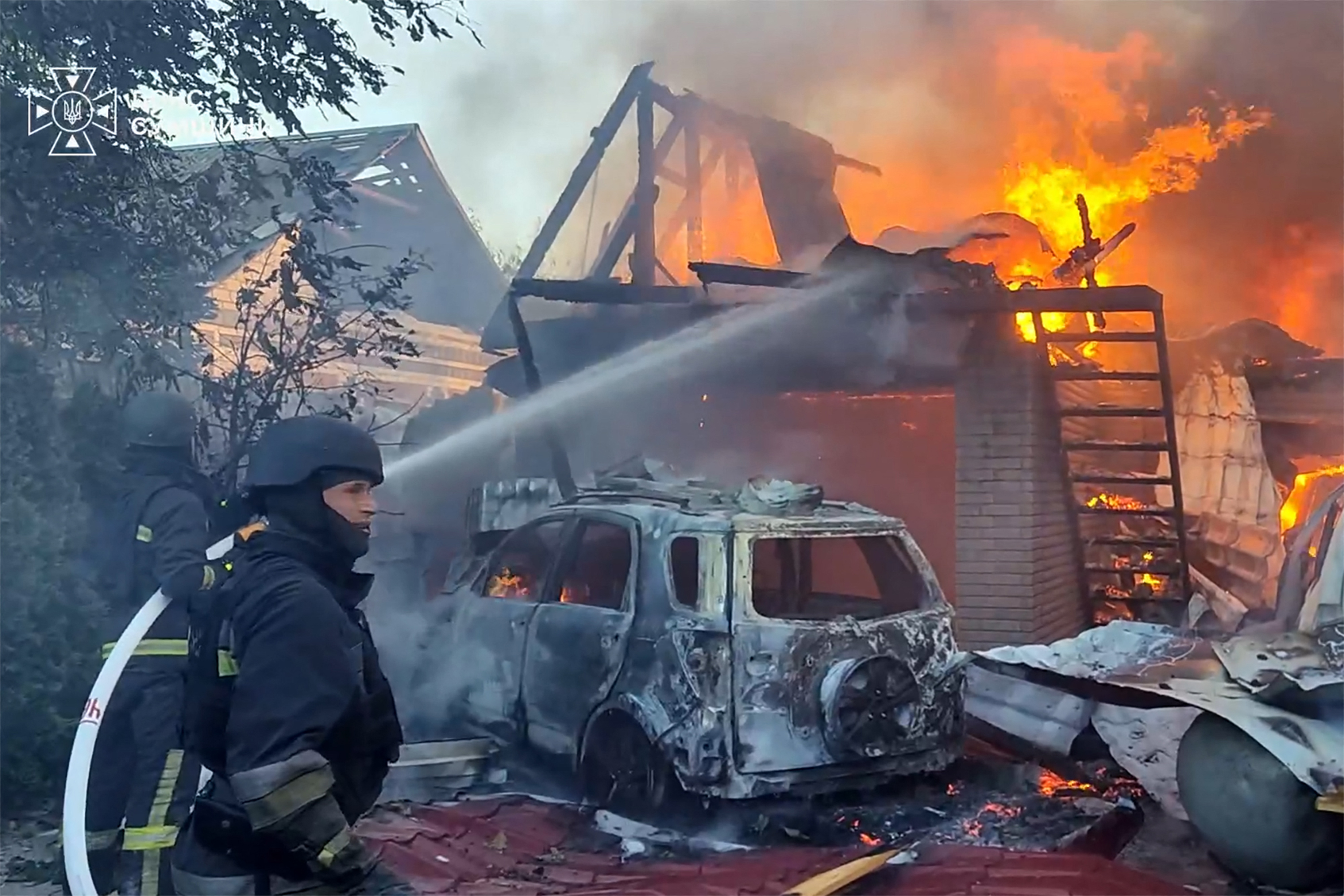 Ukrainian rescuers work to extinguish a fire in a house following an air attack at an undisclosed location in the Sumy region