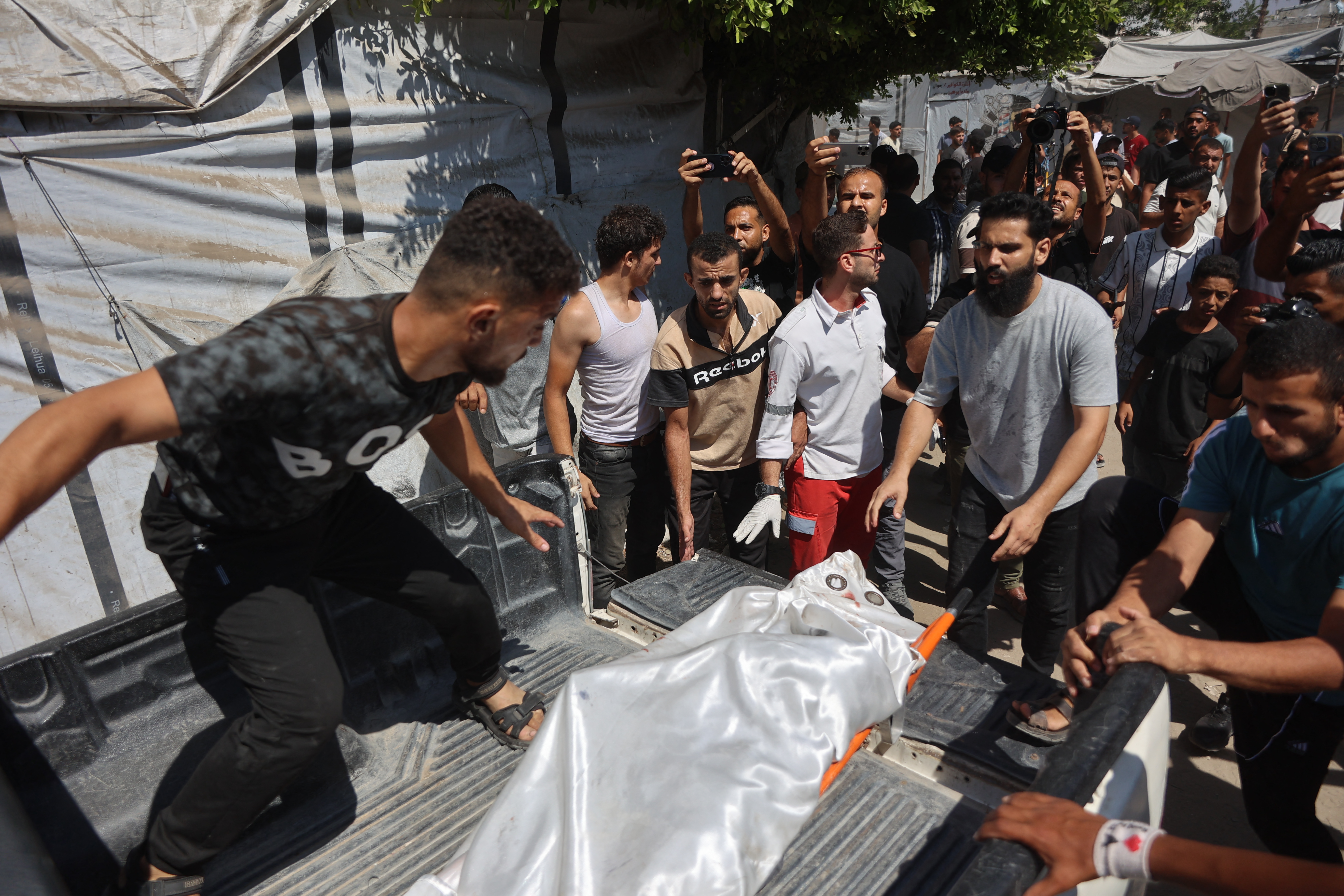 EDITORS NOTE: Graphic content / Displaced Palestinians carry the body of a victim away from the site of an Israeli strike that targeted the municipal police headquarters in Gaza City on August 19, 2026.