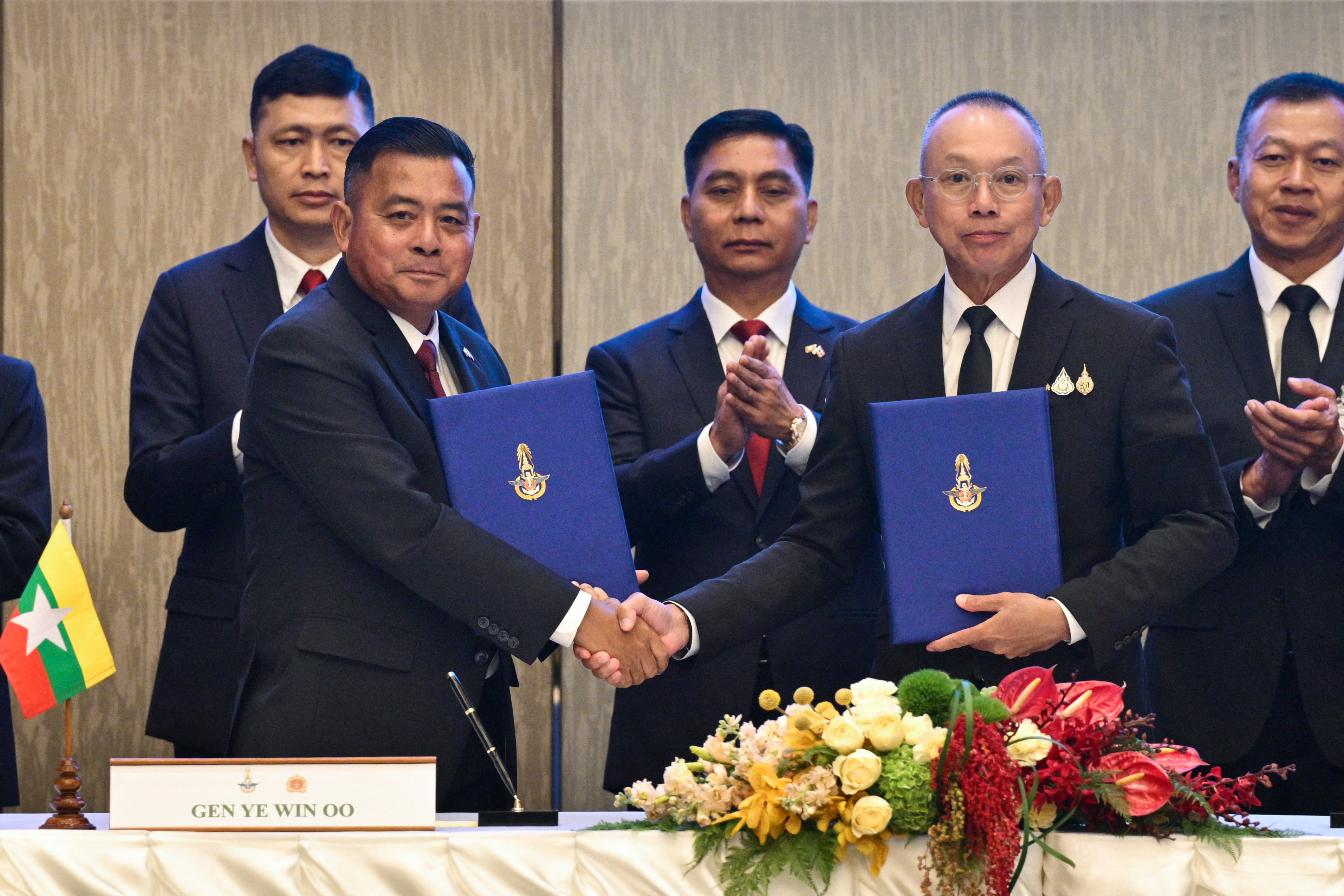 Myanmar’s military commander-in-chief, General Ye Win Oo (centre L) and Thailand’s chief of defence forces, Ukrit Boontanon (centre R) shake hands while holding files.