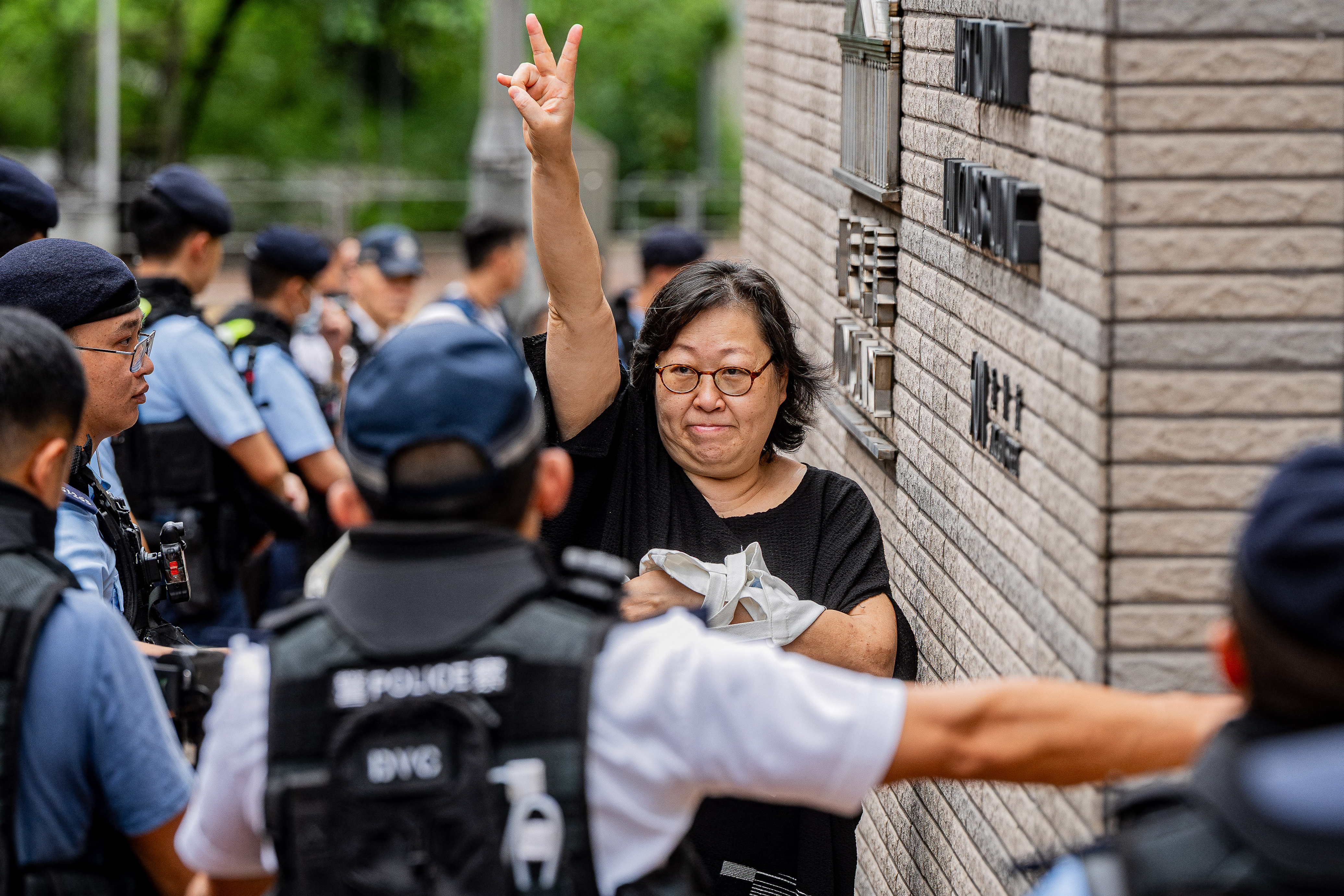 A woman gestures as she enters the West Kowloon Magistrates' Courts ahead of the verdict in the national security trial of two pro-democracy Tiananmen activists, in Hong Kong on August 21, 2026.