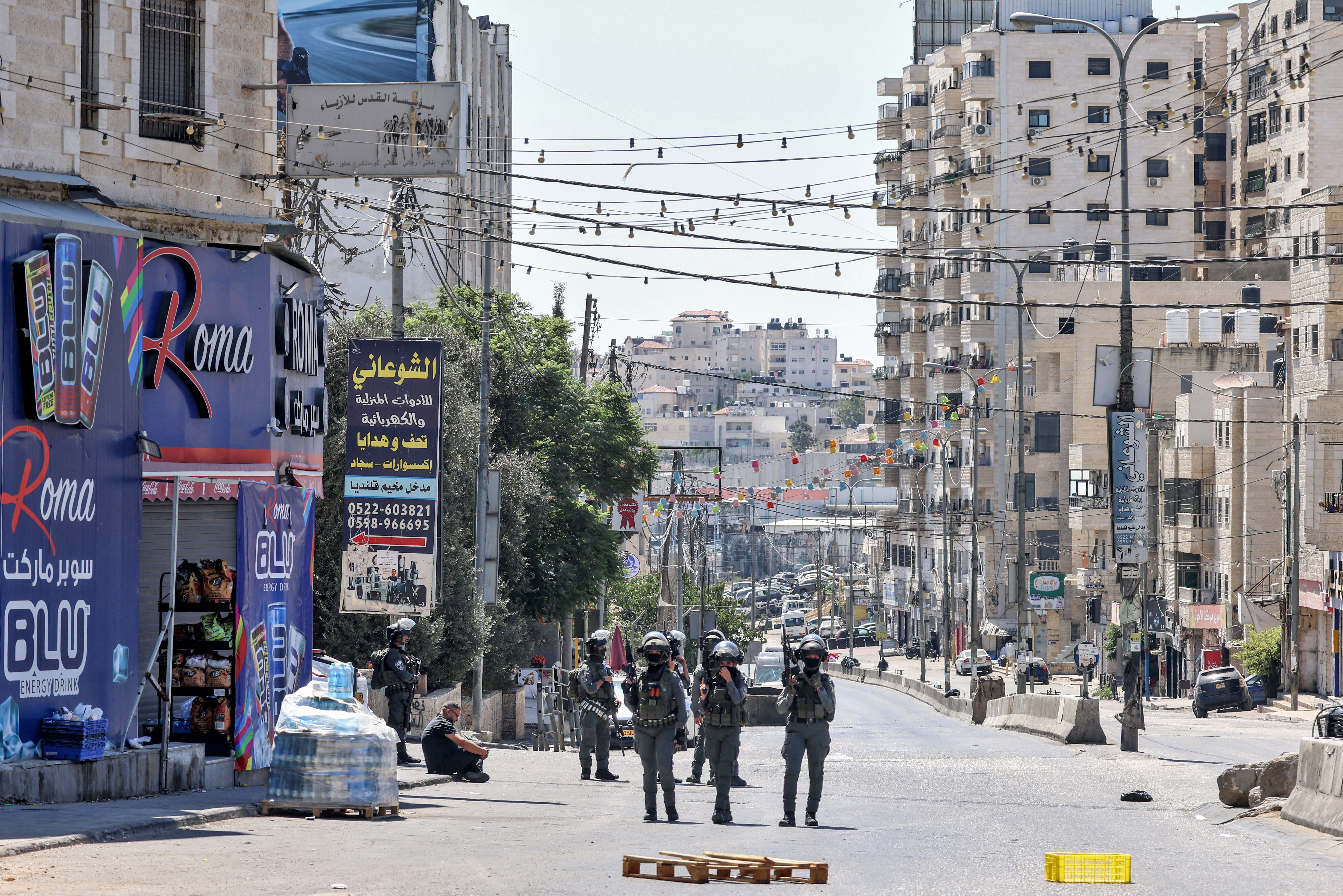 Israeli forces stand guard near a detained Palestinian man during a raid on the UNRWA Vocational Training Centre, located between the Kafr Aqab neighbourhood and the Qalandia refugee camp, south of the West Bank city of Ramallah, on August 25, 2026.