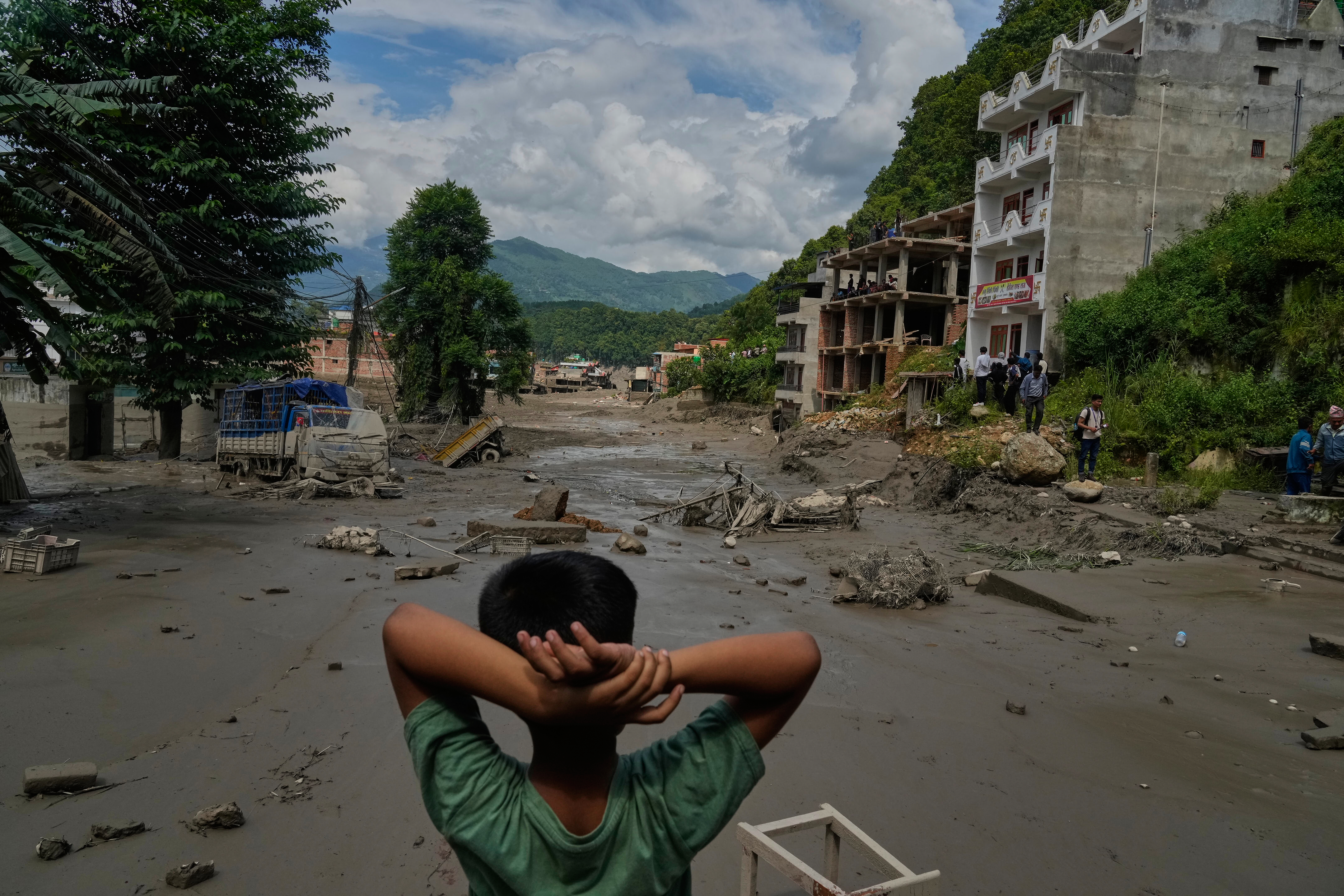 A boy looks at the devastation caused by flash flooding along the Trishuli River in Nepal's Nuwakot district, Wednesday, Aug. 26, 2026. (AP Photo/Niranjan Shrestha)