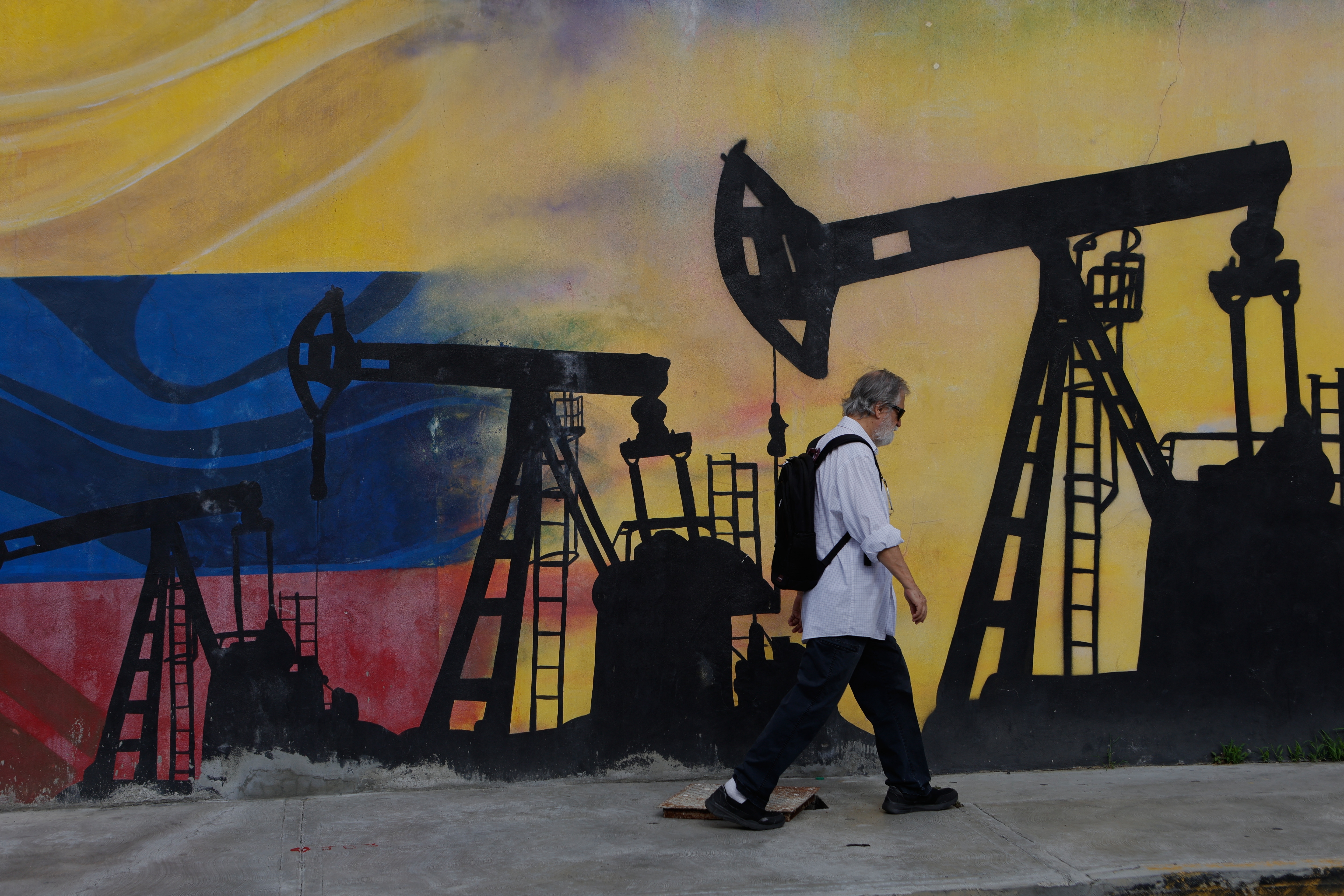 A pedestrian walks past a mural featuring oil wells in Caracas, Venezuela, Saturday, Aug 29, 2026, a day after President Donald Trump announced a deal giving the United States a stake in Venezuela’s oil reserves. (AP Photo/Pedro Mattey)
