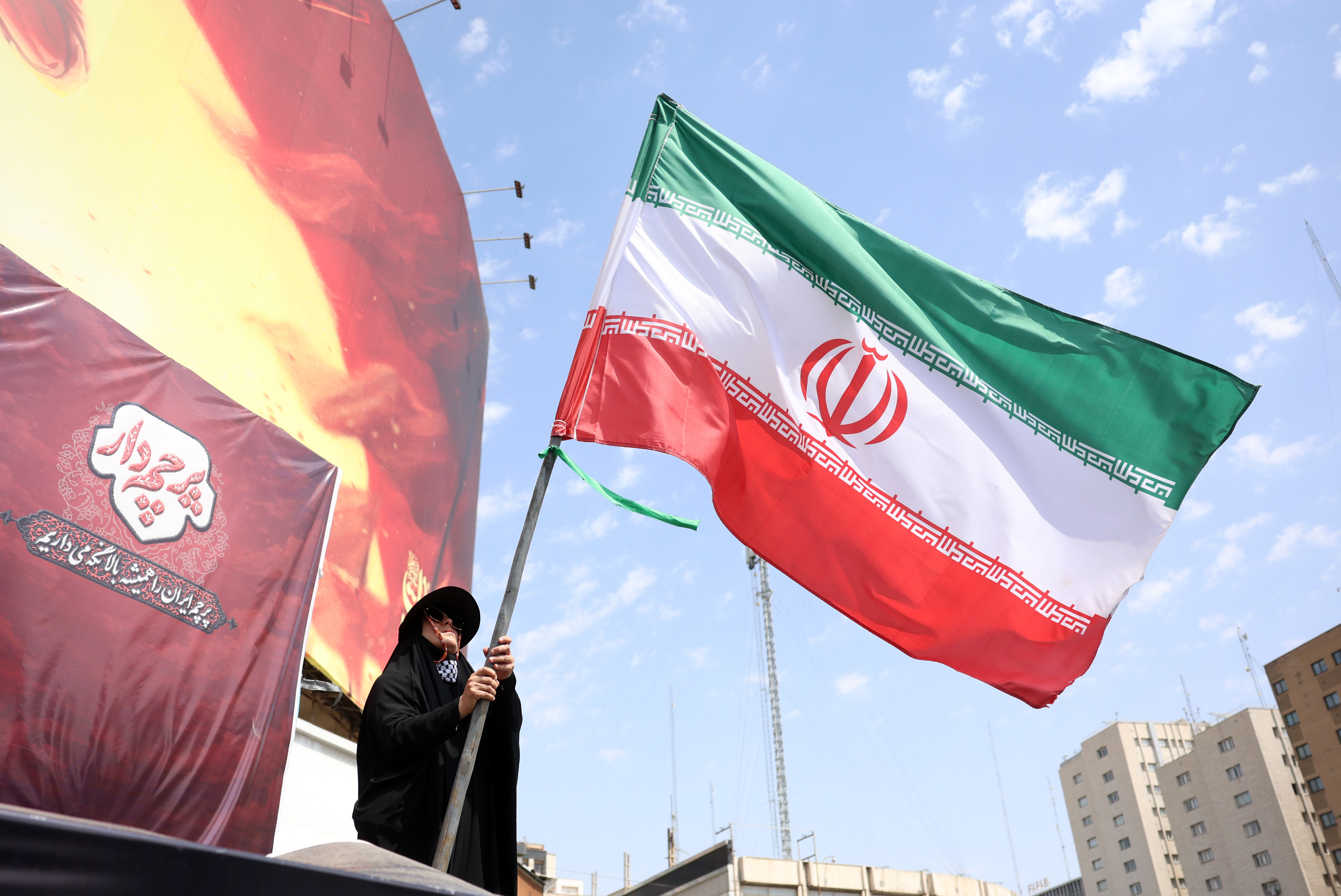 epa13175371 An Iranian woman flies Iran's national flag at the Valiasr square in Tehran, Iran, 17 August 2026. Iranian Army chief Amir Hatami announced a 30,000 US dollar bounty for killing or capturing US military personnel, offering double the reward for Iranian women who carry out the action, according to Iranian state media. EPA/ABEDIN TAHERKENAREH RESTRICTIONS: NO Access Israel Media/Persian Language TV Stations Outside Iran/Strictly No Access BBC Persian/VOA Persian/Manoto TV/Iran International TV. (As mandated by Iran's Directorate General for Foreign Media) --