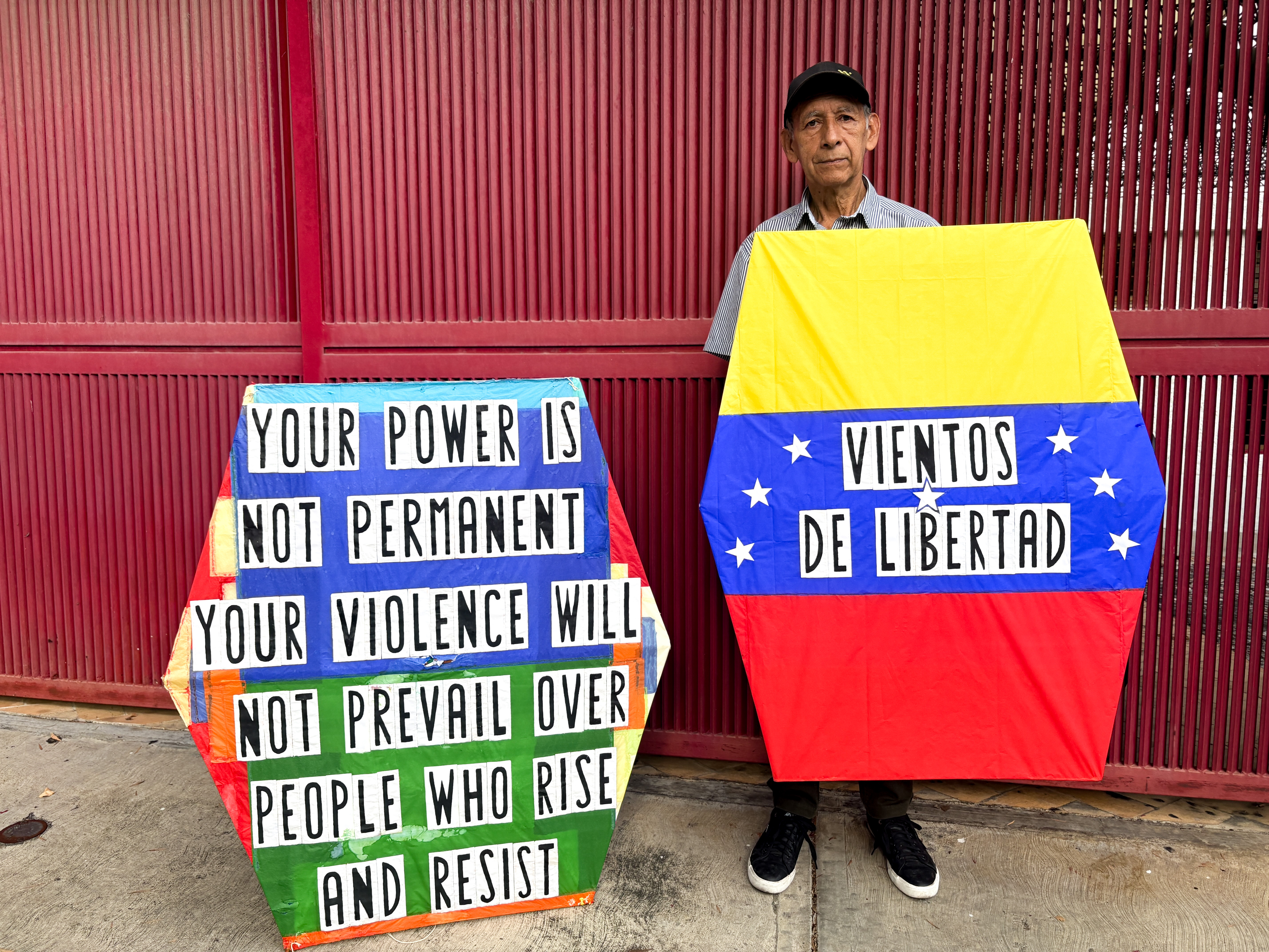 Rafael Araujo poses with two kites he made in protest of the Venezuelan government [Catherine Ellis/Al Jazeera]