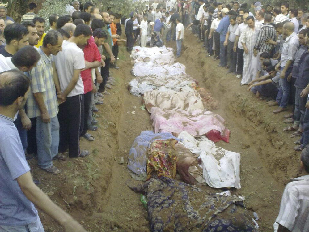 People gather during the mass burial of people whom activists say were killed by forces loyal to Syria's President Bashar al-Assad, in Artouz, near Damascus, August 1, 2012. [Shaam News Network/Reuters]