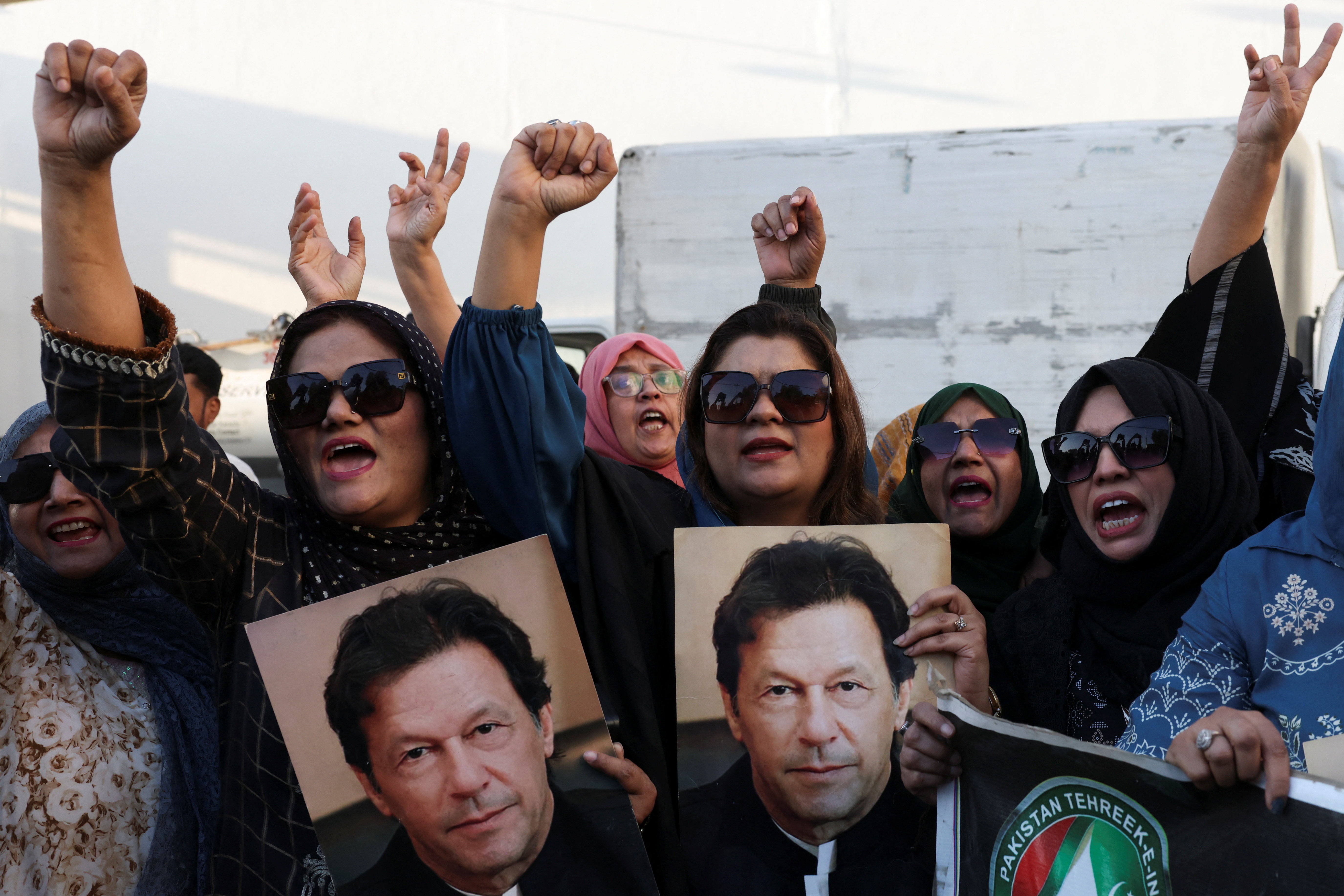 People shout slogans as they hold up pictures of Imran Khan.