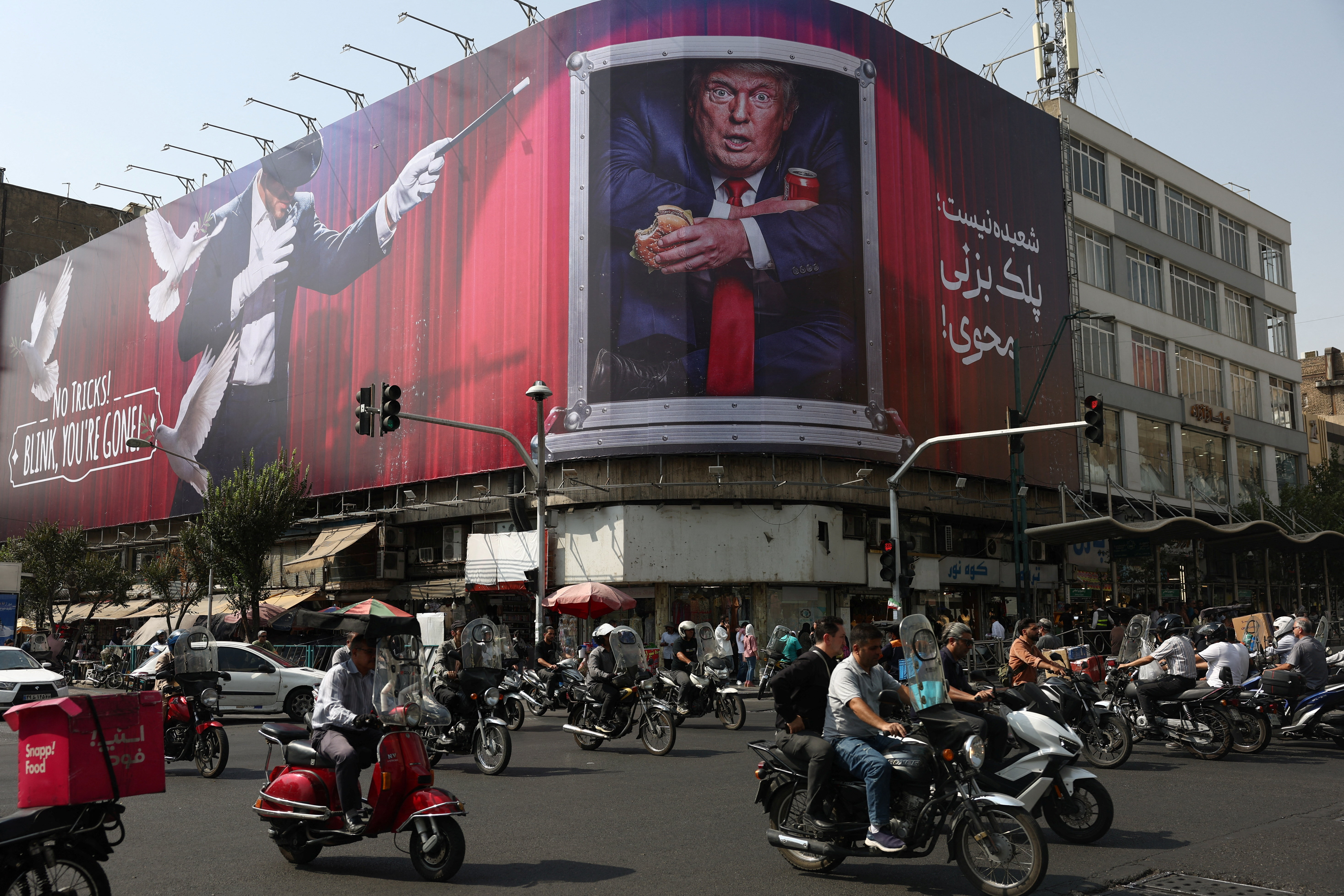 People drive near a billboard depicting US President Donald Trump on a building.