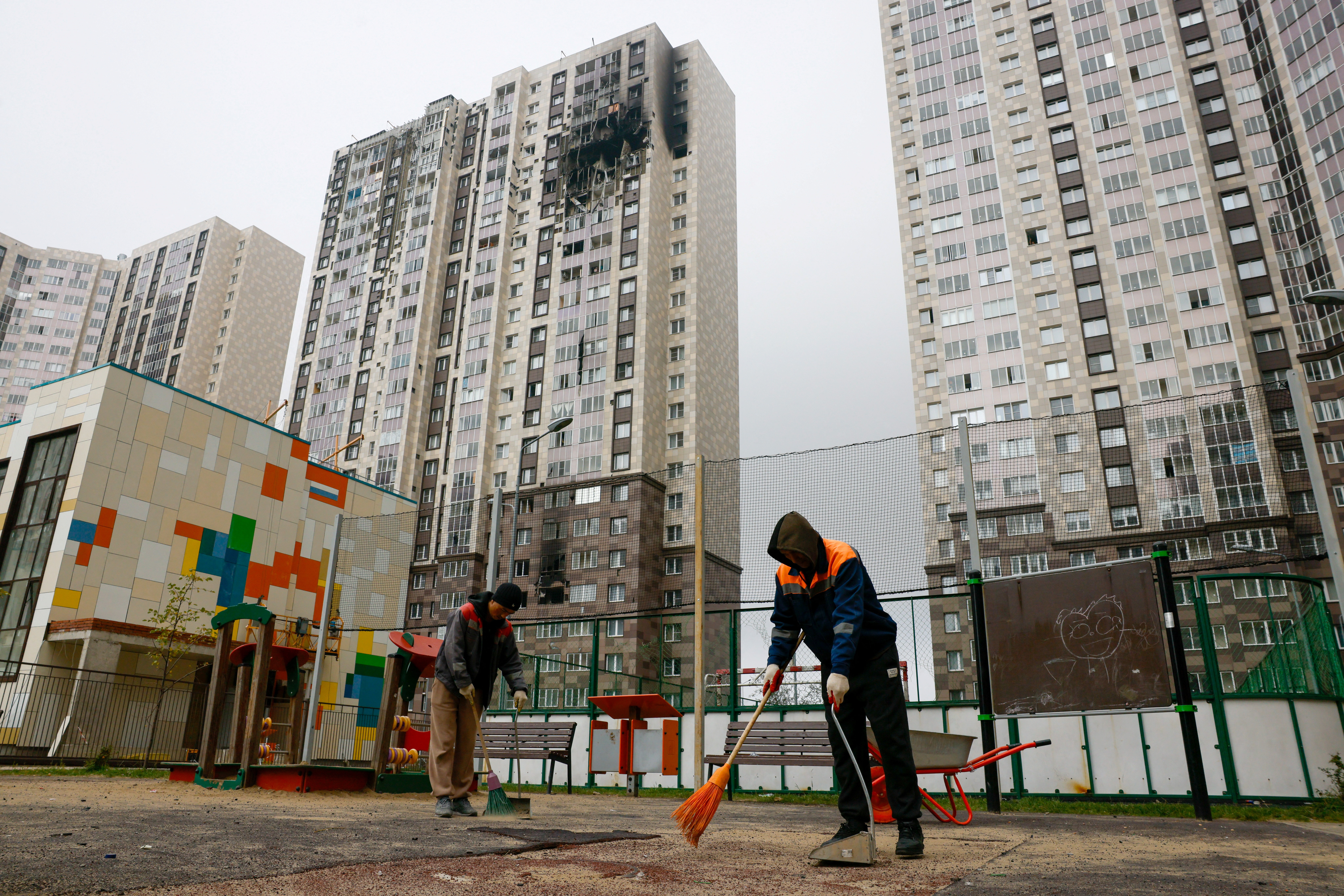Workers sweep the courtyard of a damaged multi-storey residential building hit by what authorities described as a Ukrainian drone strike