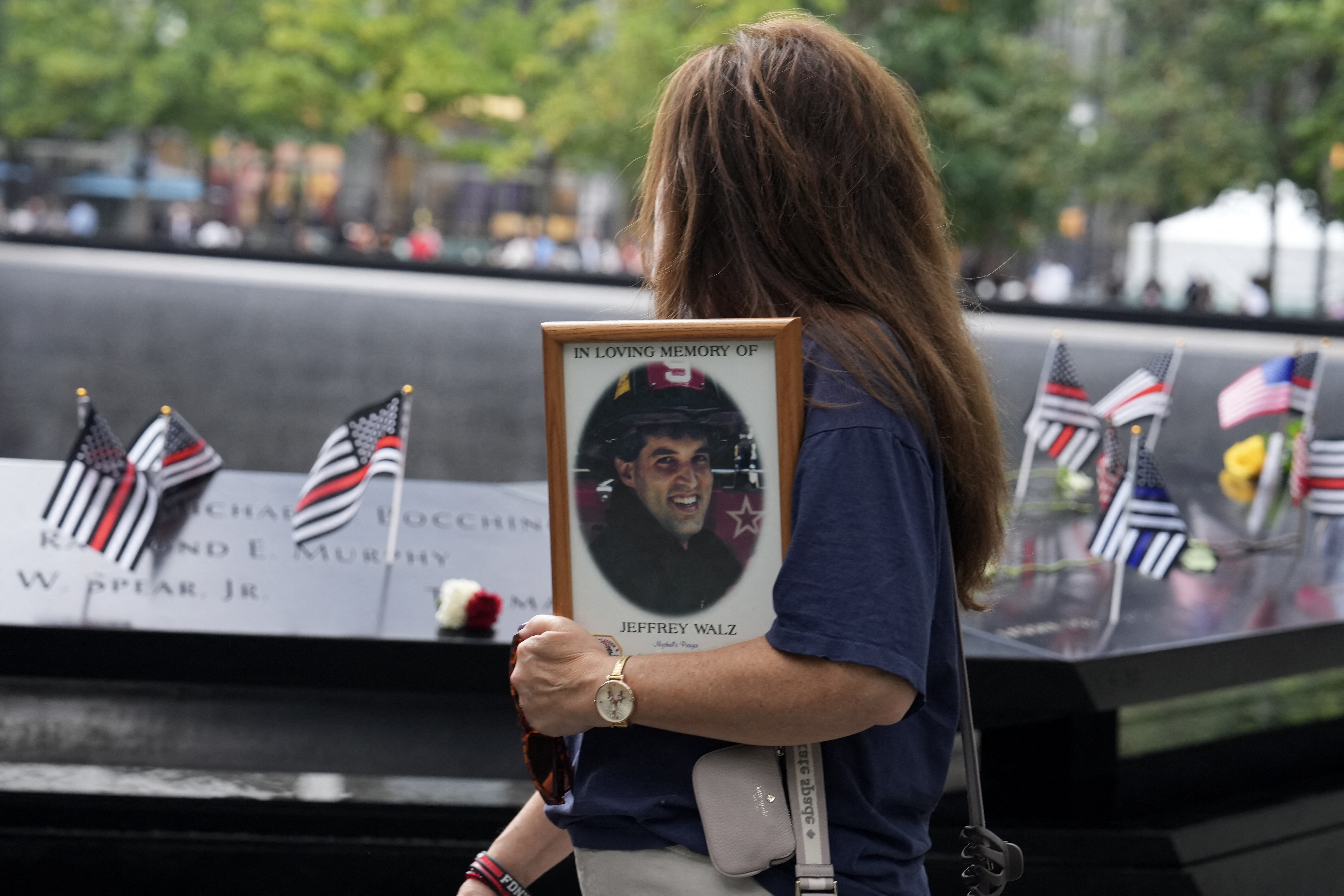 A person holding a picture stands at the memorial ahead of the the 25th anniversary commemoration of the September 11, 2001 attacks at the National September 11 Memorial in New York on September 11, 2026. (Photo by DAVID DEE DELGADO / POOL / AFP)