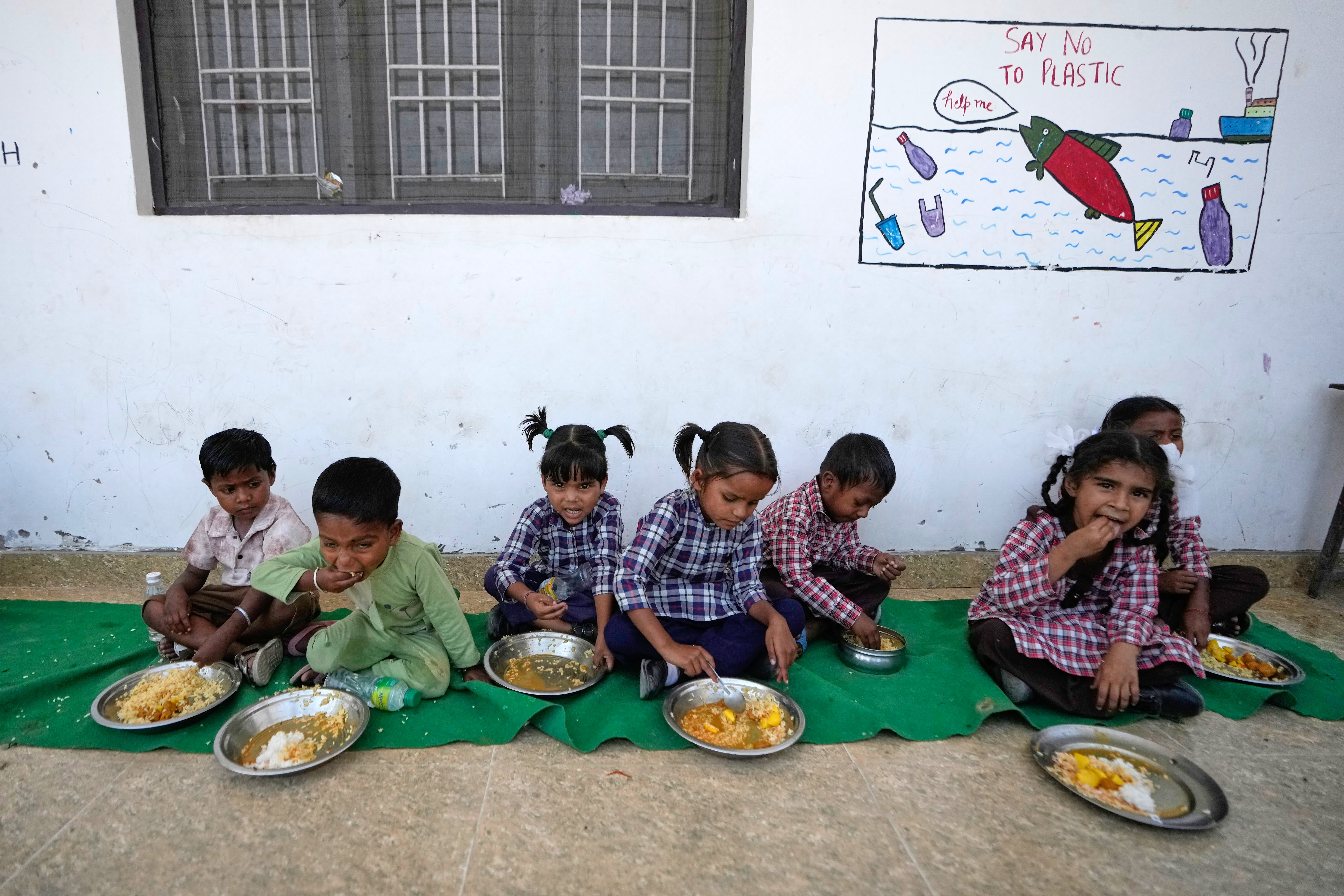 Indian school children eat their mid-day meal at a government-run school in Ganjansoo village near the India Pakistan International Border in Jammu, India, Wednesday, May 13, 2026. Poor quality mid-day meals have been a trigger for some of the recent school protests