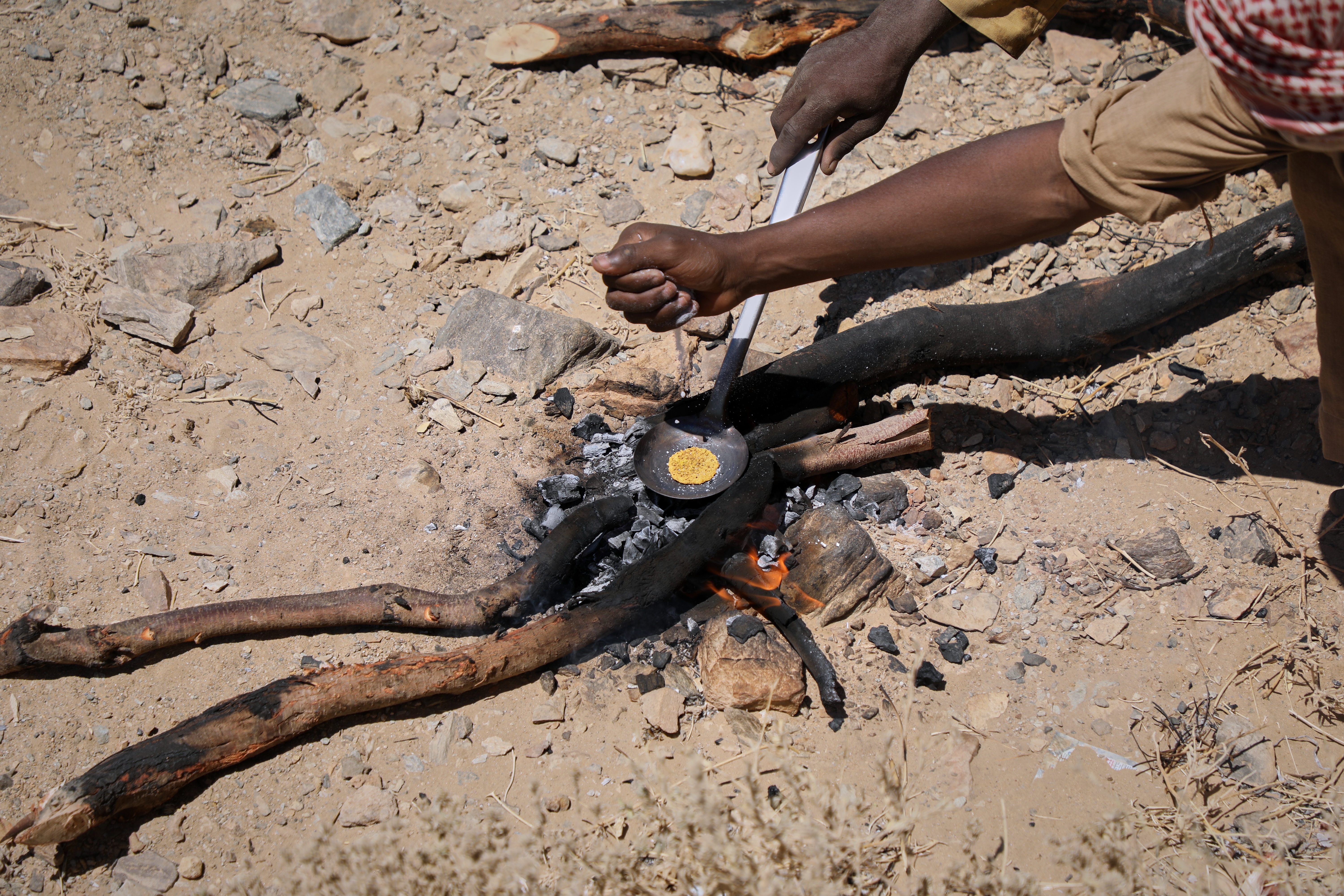 Miners heat processed gold concentrate over an open fire at an artisanal mining site in Dalago Mahas, Sudan's Northern State, Friday, May 8, 2026.(AP Photo/Mohnd Blal)
