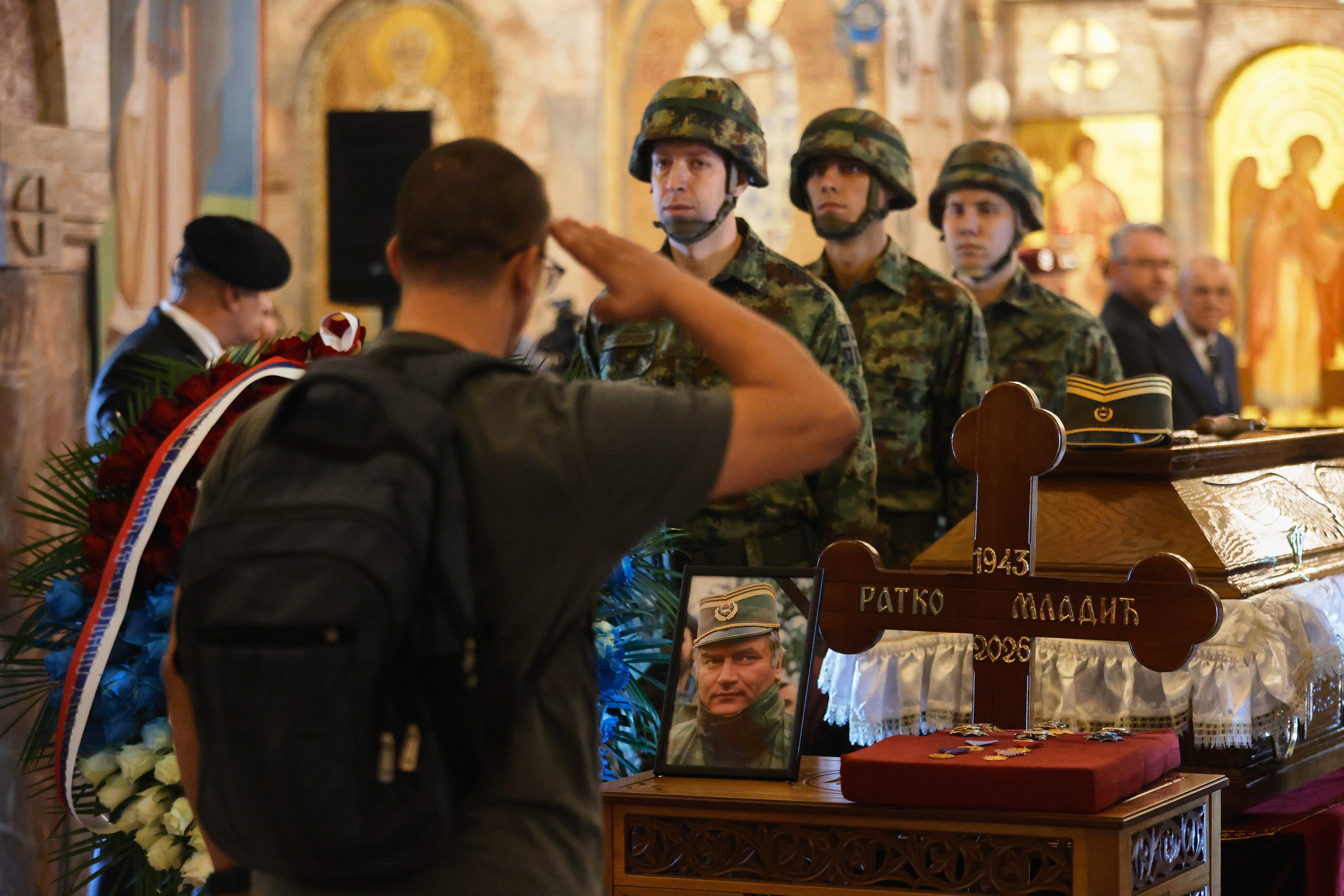 A man salutes as Serbian national military servicemen stand around the coffin of the former Bosnian Serb army commander Ratko Mladic, who died last week while serving a life sentence for genocide and other atrocities during the war in Bosnia, at the St. Luka Church, in Belgrade, Serbia, Monday, Sept. 7, 2026. (AP Photo/Marko Drobnjakovic)