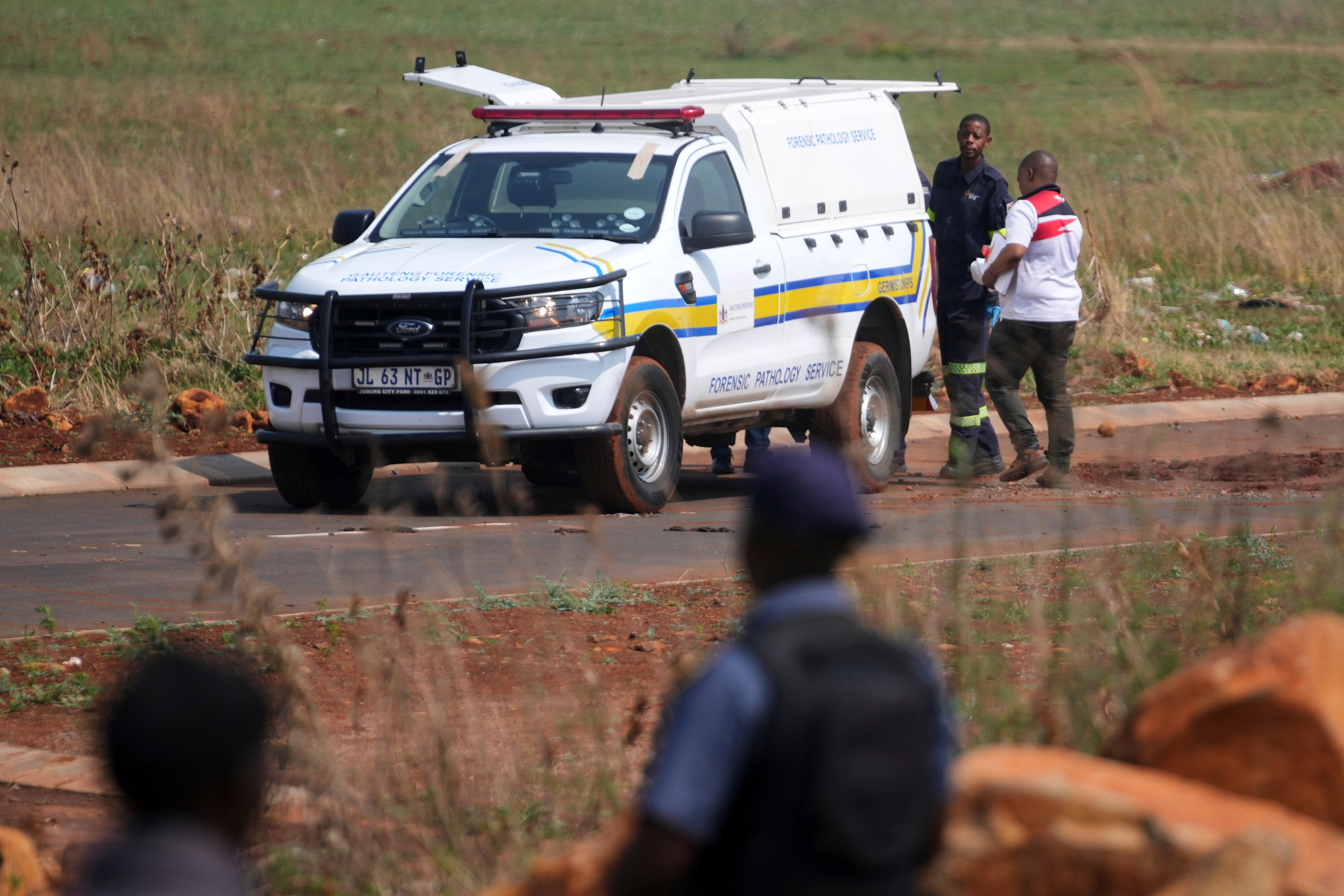 Forensic investigators work at the site where the body of a woman was discovered on the outskirts of Johannesburg, South Africa, Thursday, Sept. 17, 2026. (AP Photo/Themba Hadebe)