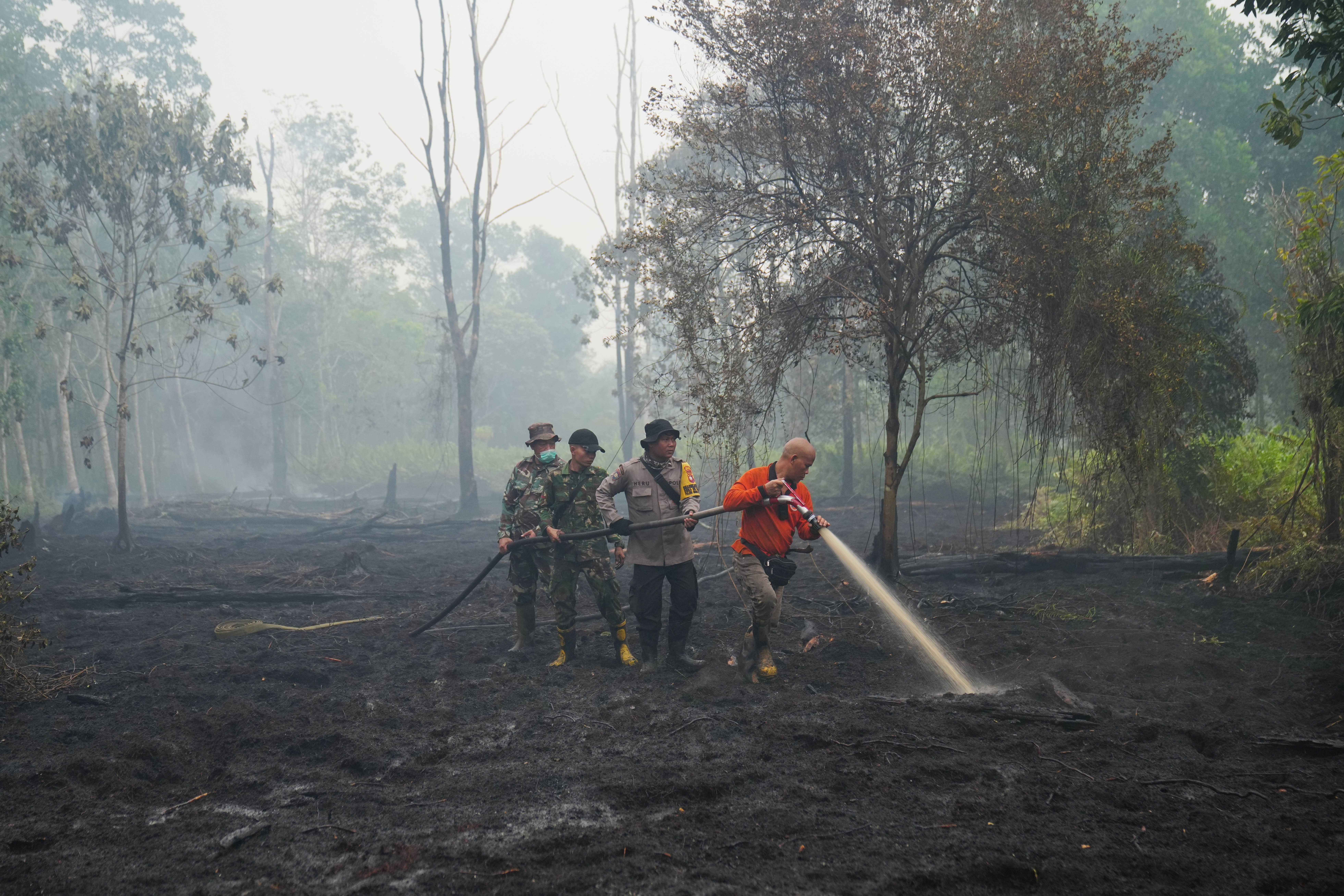 Firefighters spray water to put out wildfires burning through a peatland forest in Kubu Raya, West Kalimantan, Indonesia on September 12, 2026.