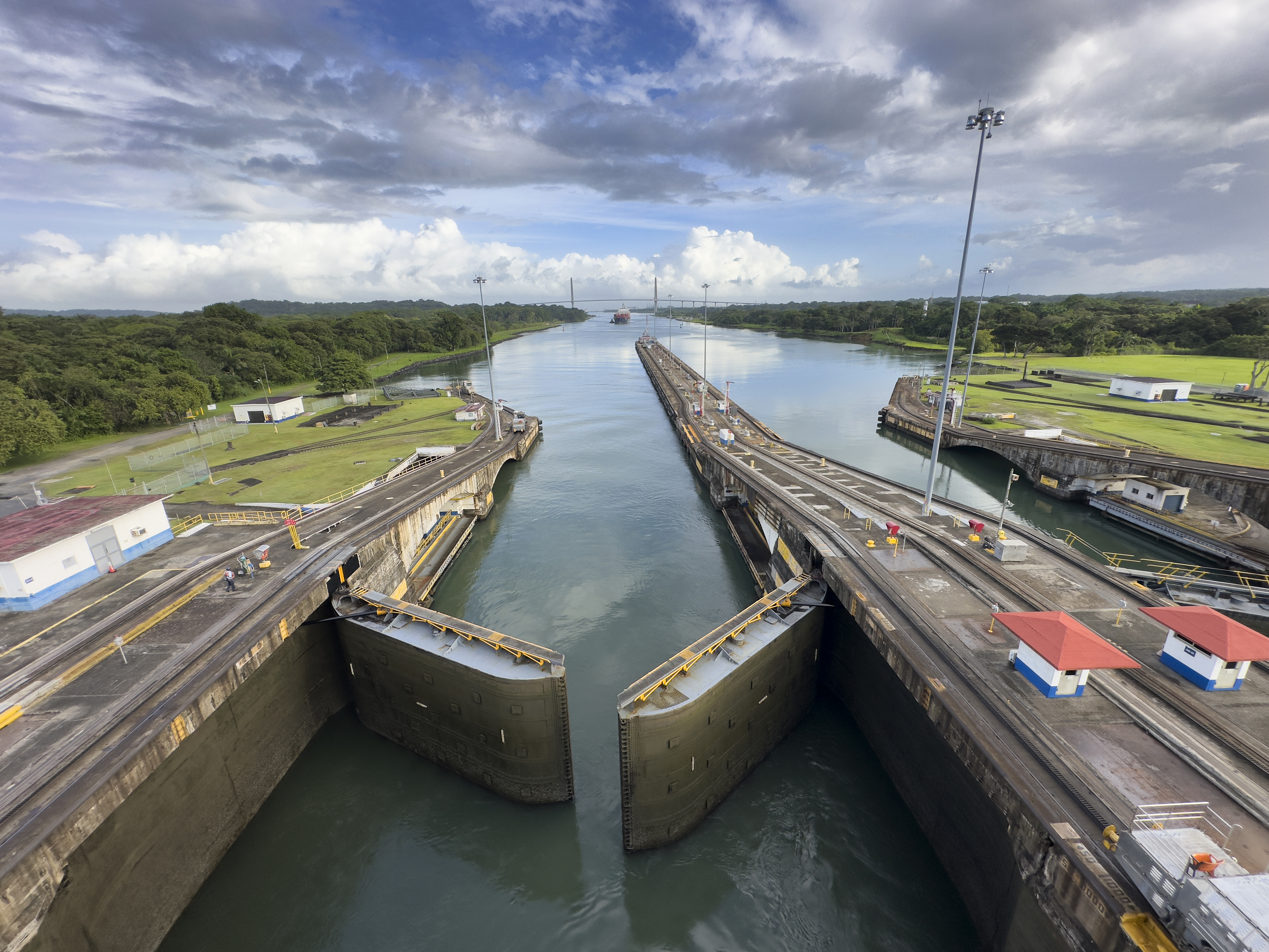 Aerial perspective of the Panama Canal's Miraflores Locks system, showing the massive water chambers and lock gates. The engineering marvel demonstrates the canal's essential role in global maritime commerce, with its distinctive green-tinted water contrasting against the concrete structure.