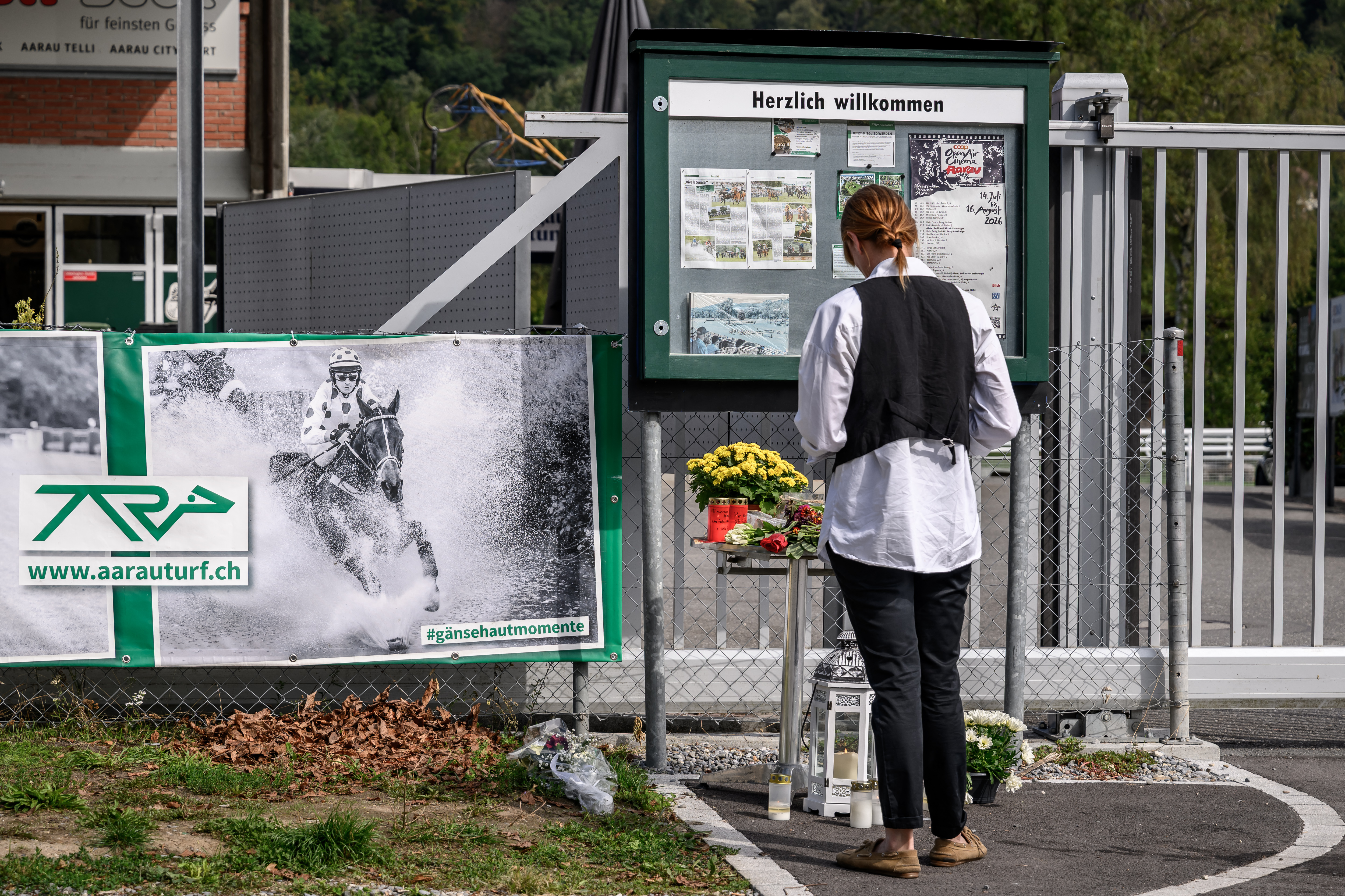 A woman stand next to a makeshift memorial at the entrance of the Schachen horse racing track, following a shooting at a rave party in Aarau, northern Switzerland, on September 2, 2026.
