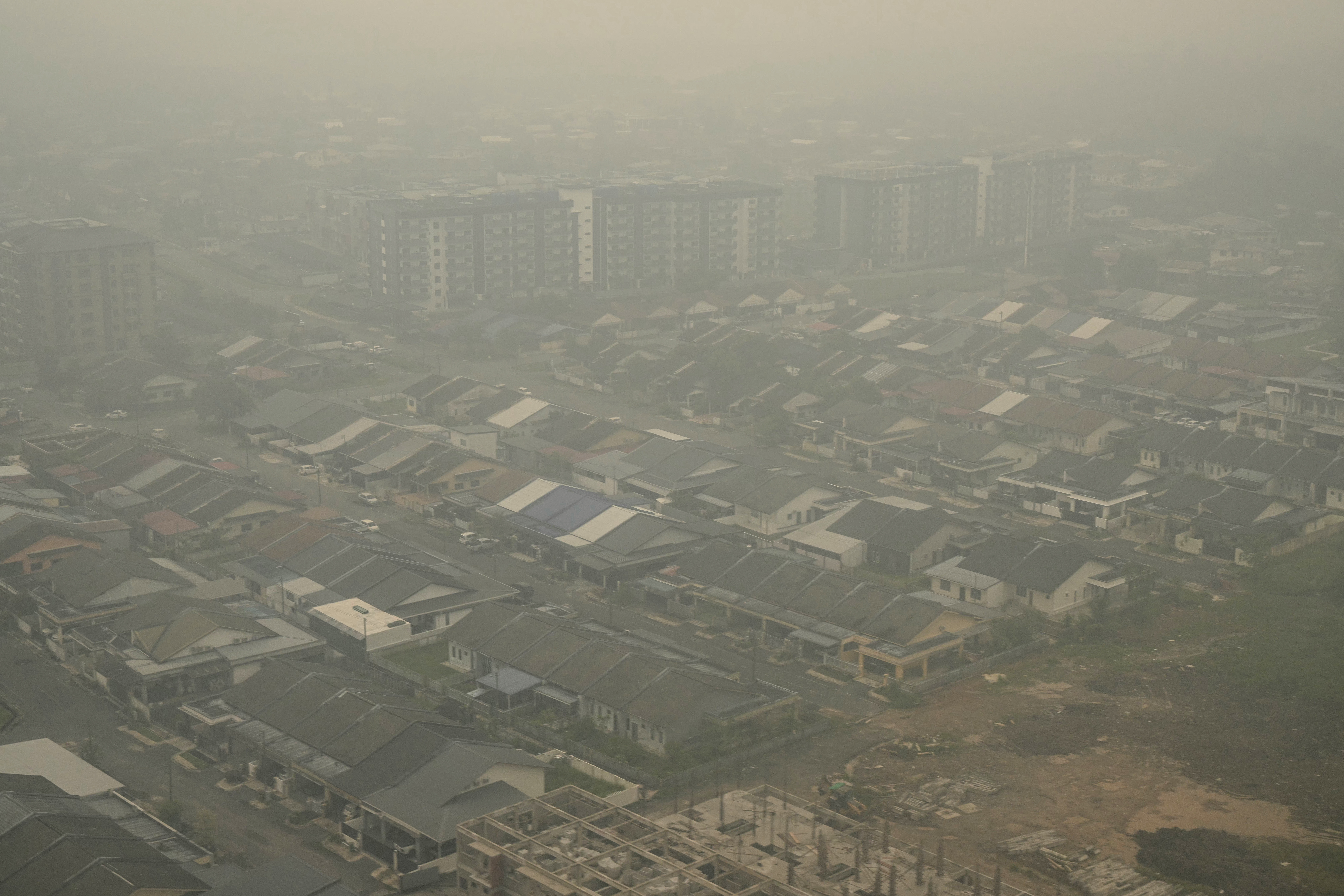 This aerial photo taken from a commercial plane shows haze from Indonesian forest fires blanketing a residential district in Kuching, the capital city of Sarawak state on the island of Borneo on September 5, 2026. (Photo by MOHD RASFAN / AFP)