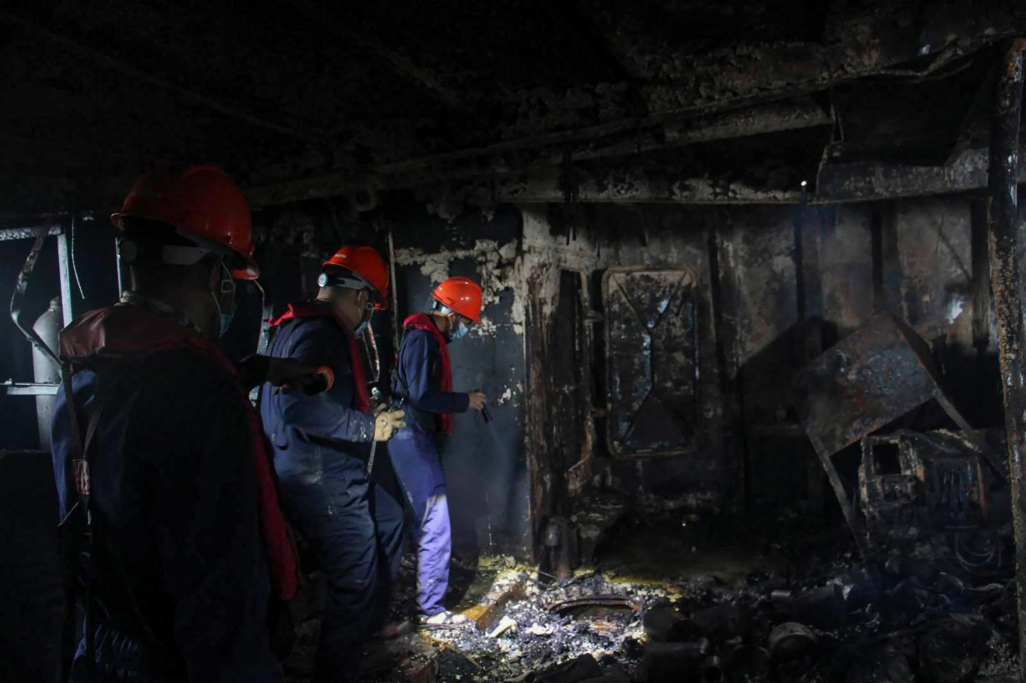 This handout photo taken on September 11, 2026 and released by the Philippine Coast Guard (PCG) shows coast guard personnel inspecting a burnt section of the M/V June Aster off the shores of Coron town, Palawan province.