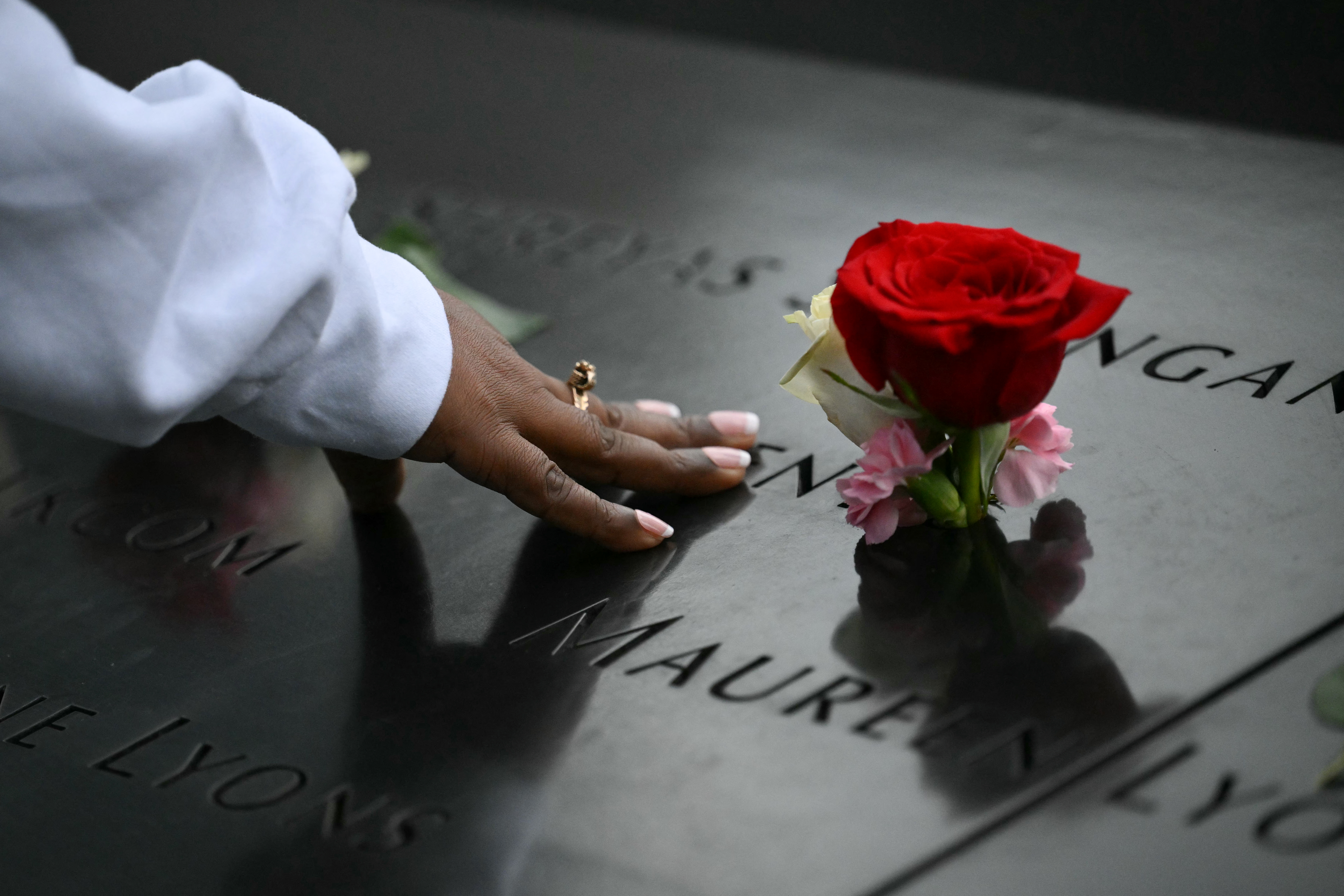 A person touches a name on the memorial during the 25th anniversary commemoration of the September 11, 2001 attacks at the National September 11 Memorial in New York on September 11, 2026. (Photo by ANGELA WEISS / AFP)