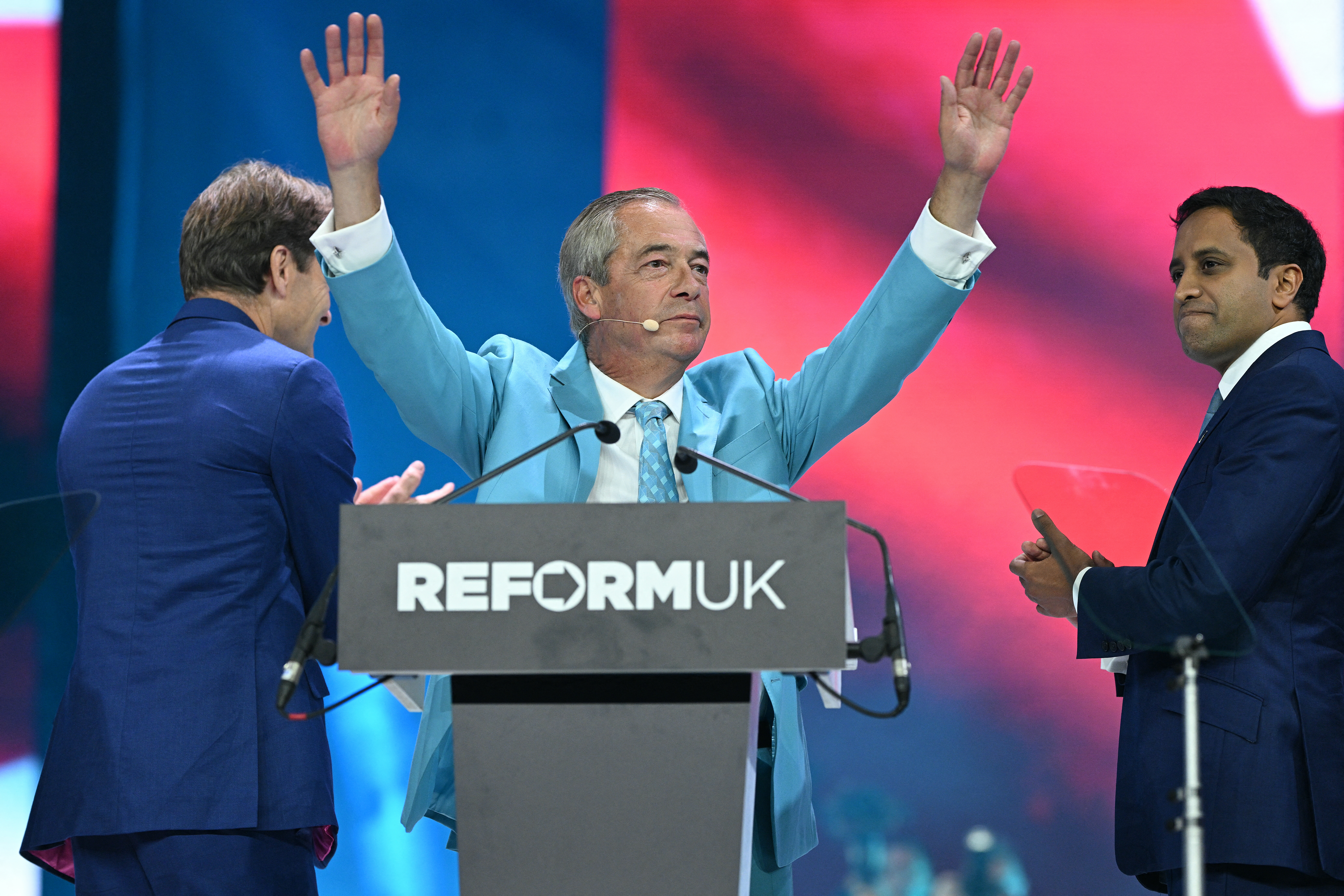Reform UK Leader Nigel Farage (C), flanked by Deputy Leader Richard Tice (L) and shadow Home Secretary Zia Yusuf, at the end of his address on the third day of the party's annual conference