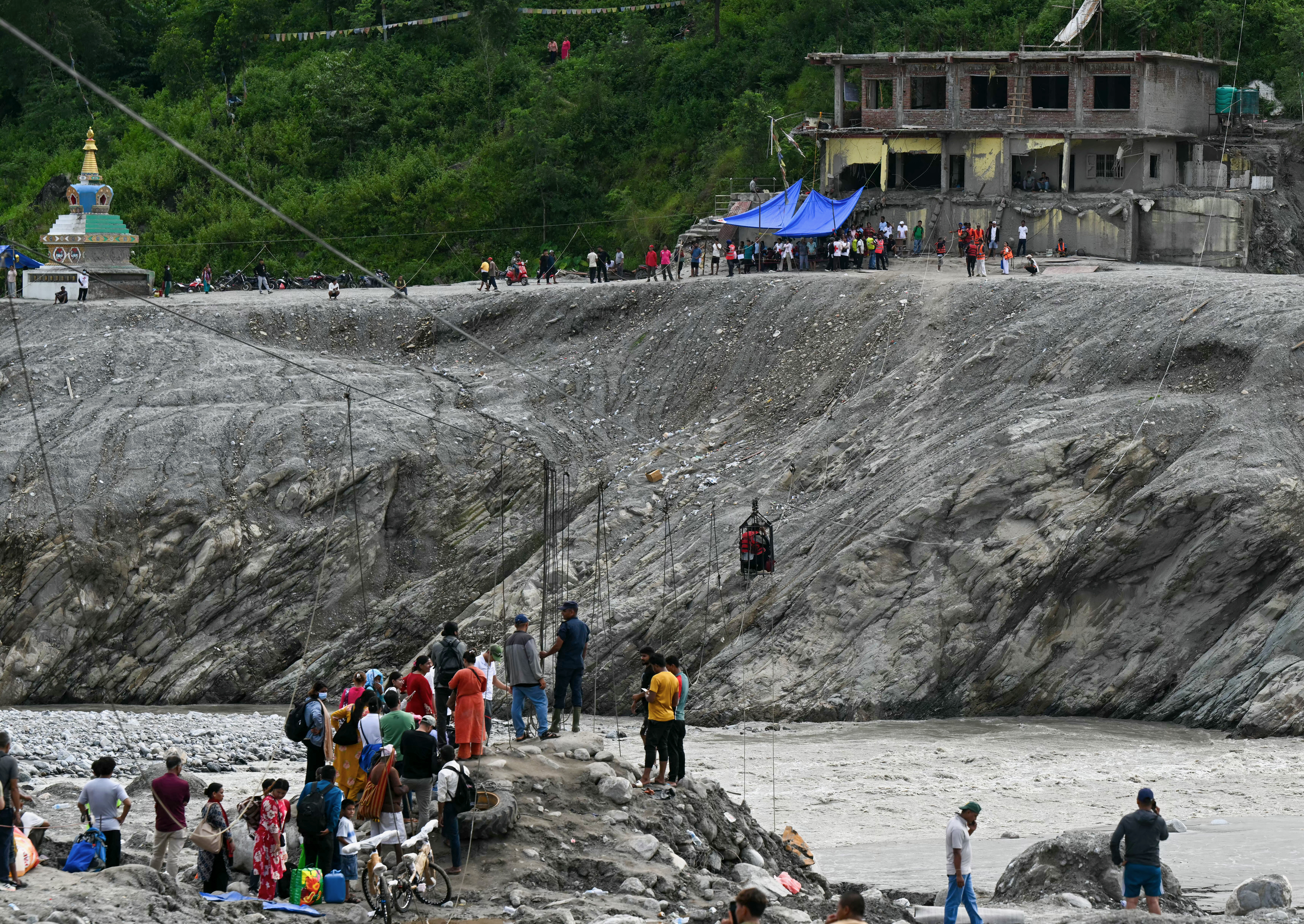 People cross a river via a zip line in the aftermath of flash floods at Trishuli in Nepal’s Nuwakot district on September 11, 2026.