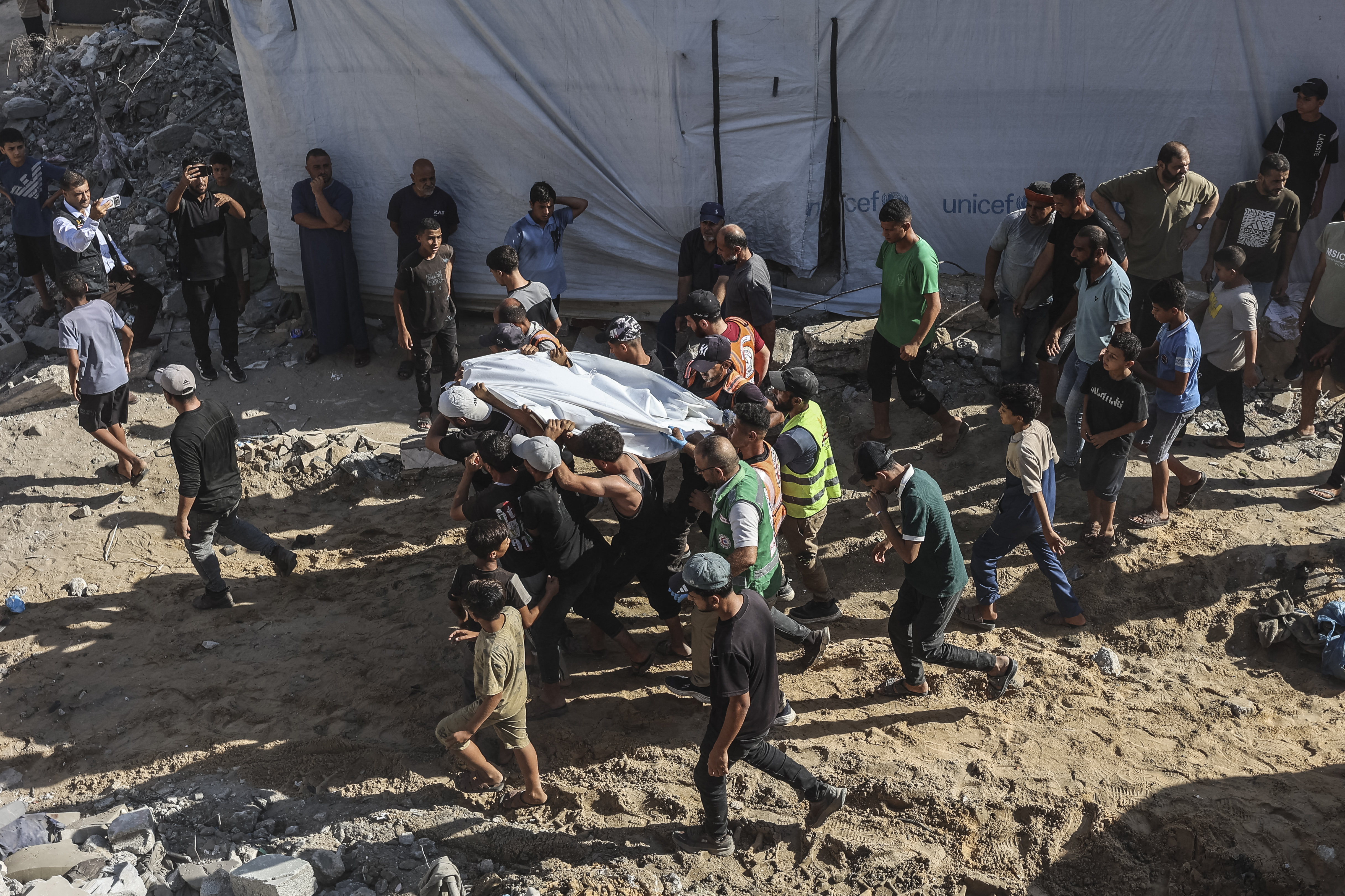 Volunteers and rescuers carry a body recovered from the rubble of a collapsed building in the Tal al-Hawa area of Gaza City on September 16, 2026.