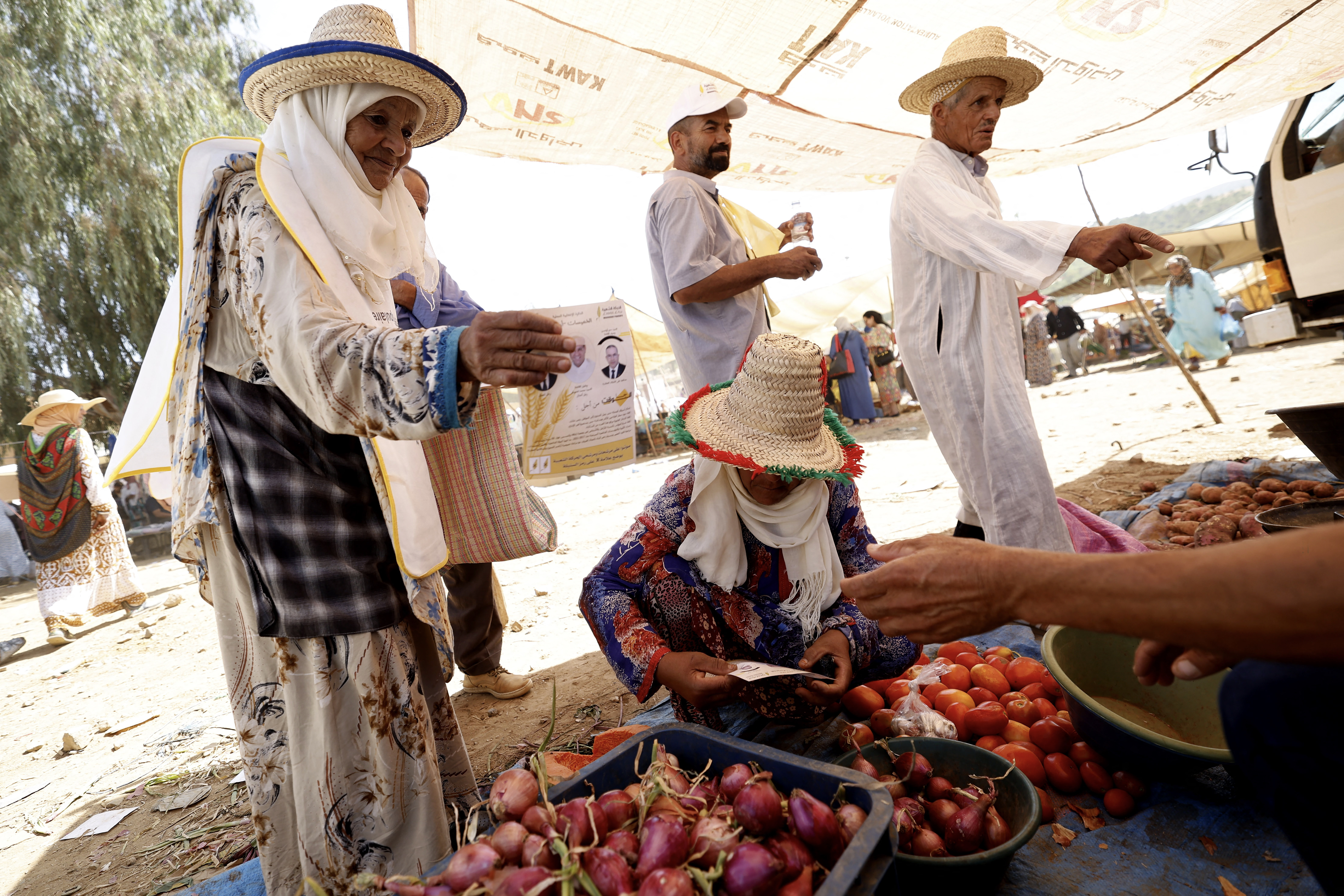 Campaigners for the Popular Movement (MP) hand out leaflets to merchants at the weekly souk in the rural commune of Ait Ikkou, in the Khemisset region, on September 19, 2026, before Morocco’s legislative elections [AFP]