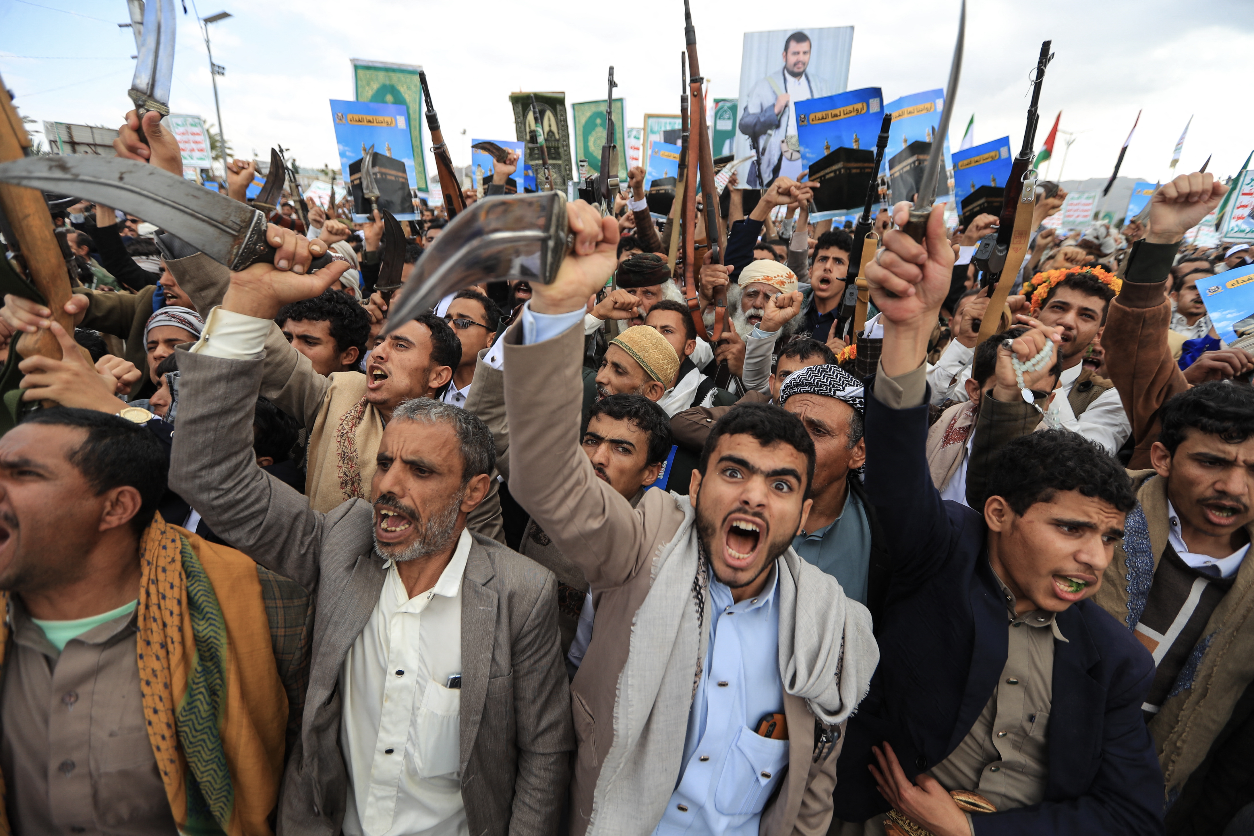 Supporters of the Houthi authorities brandish their weapons and hold placards showing the Kaaba and reading "For it, we willingly offer our souls" during a protest against the Saudi intervention in Yemen and against Saudi Arabia's recent accusation that the Houthis fired at the holy city of Mecca, in Sanaa on September 18, 2026.
