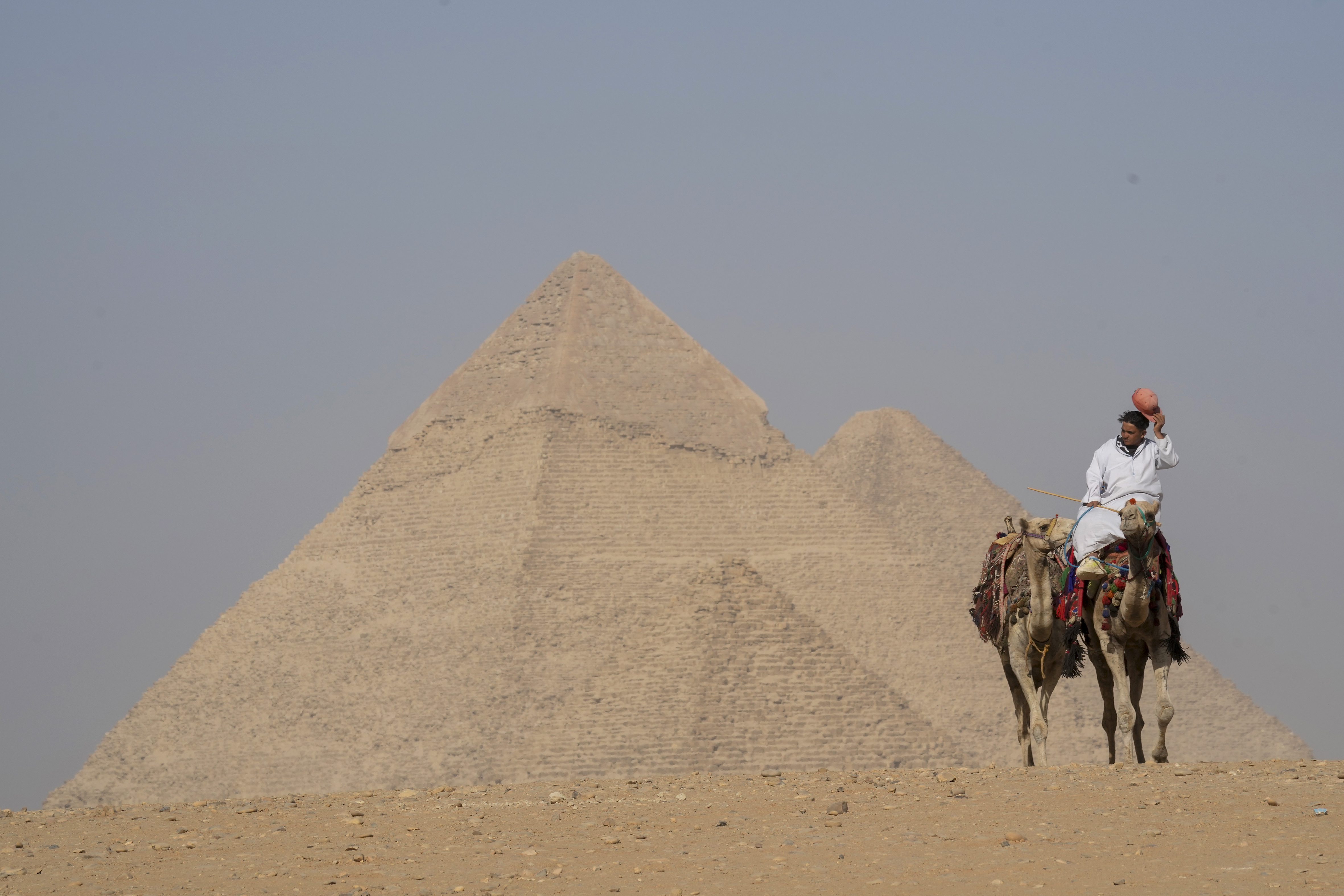 A tourist guide rides a camel in front of the historical site of the Pyramids of Giza, on the outskirts of Cairo, Egypt, Thursday, Oct. 24, 2024. (AP Photo/Amr Nabil)